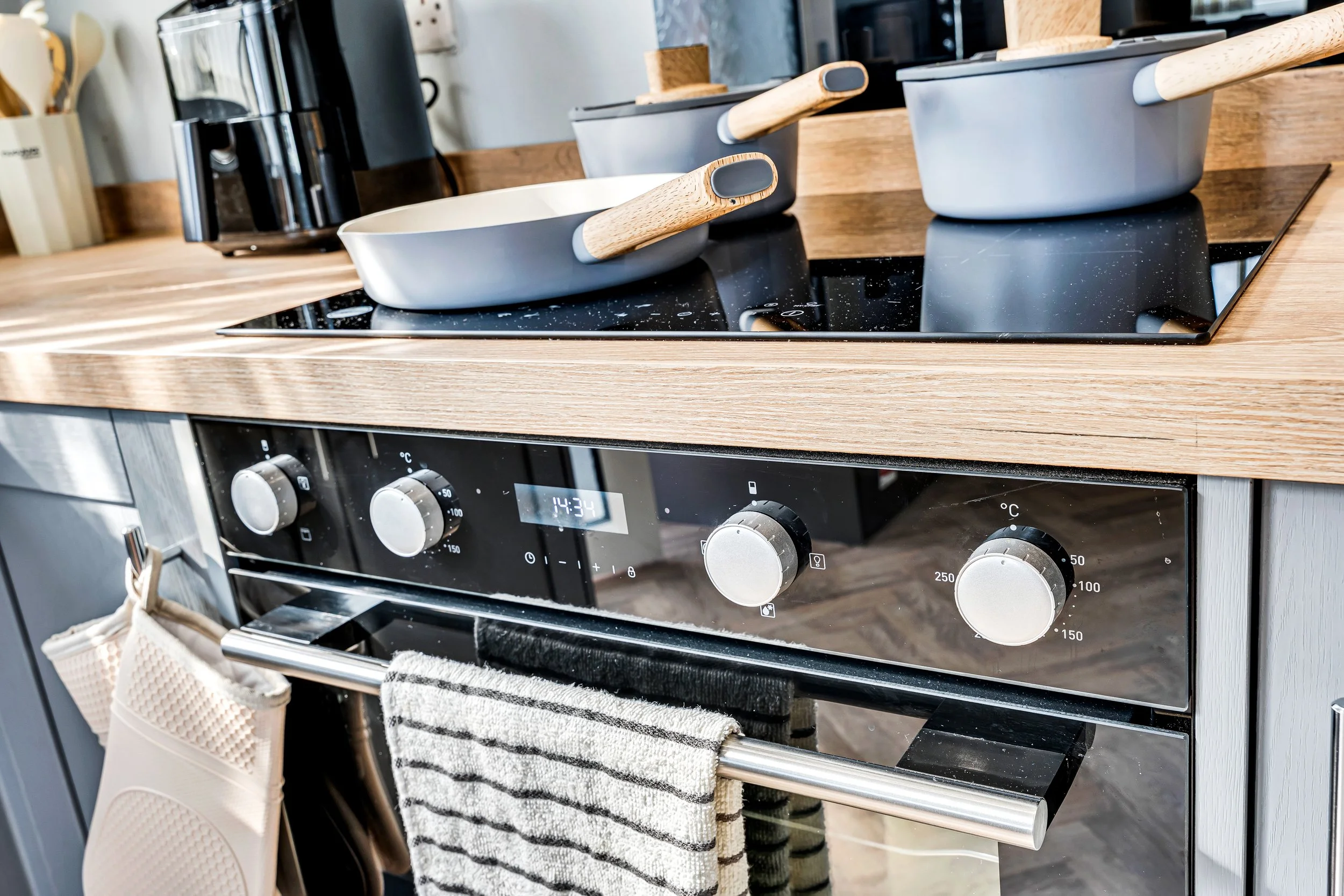 Kitchen stove with three pots and a towel hanging from the oven handle.