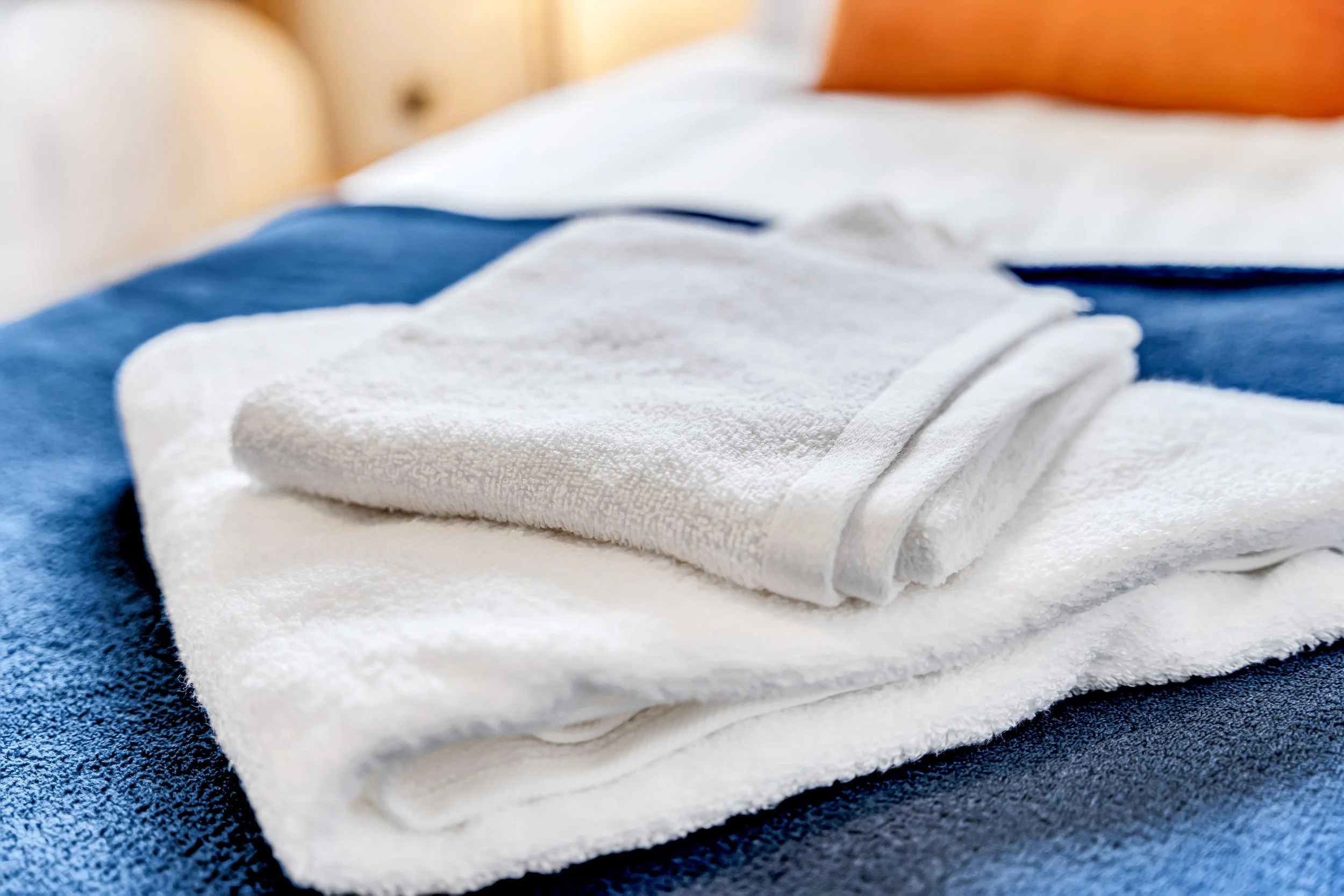 Stacked white towels on a blue bedspread.