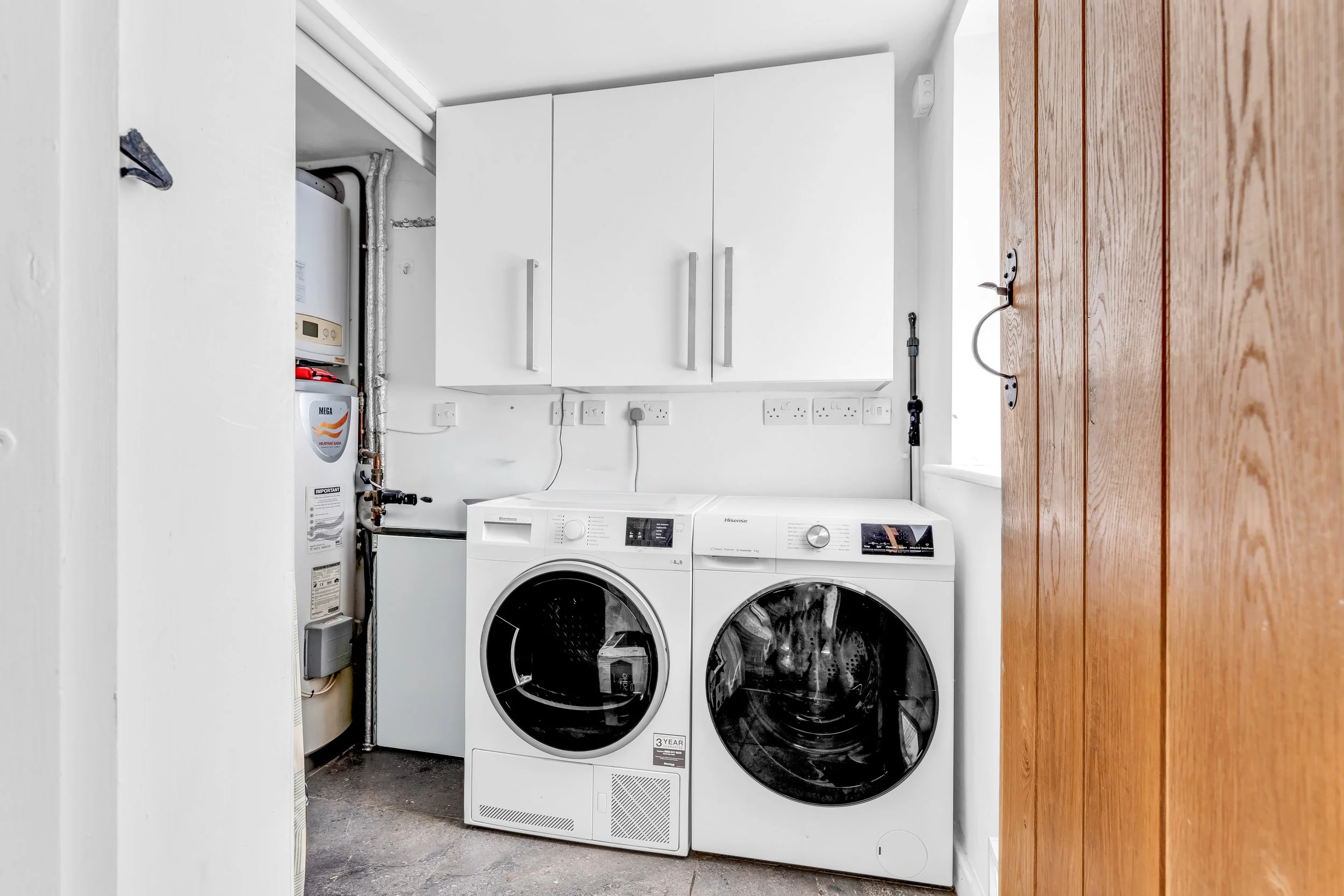 Laundry room with washing machine, dryer, white cabinets, water heater, and electrical outlets.