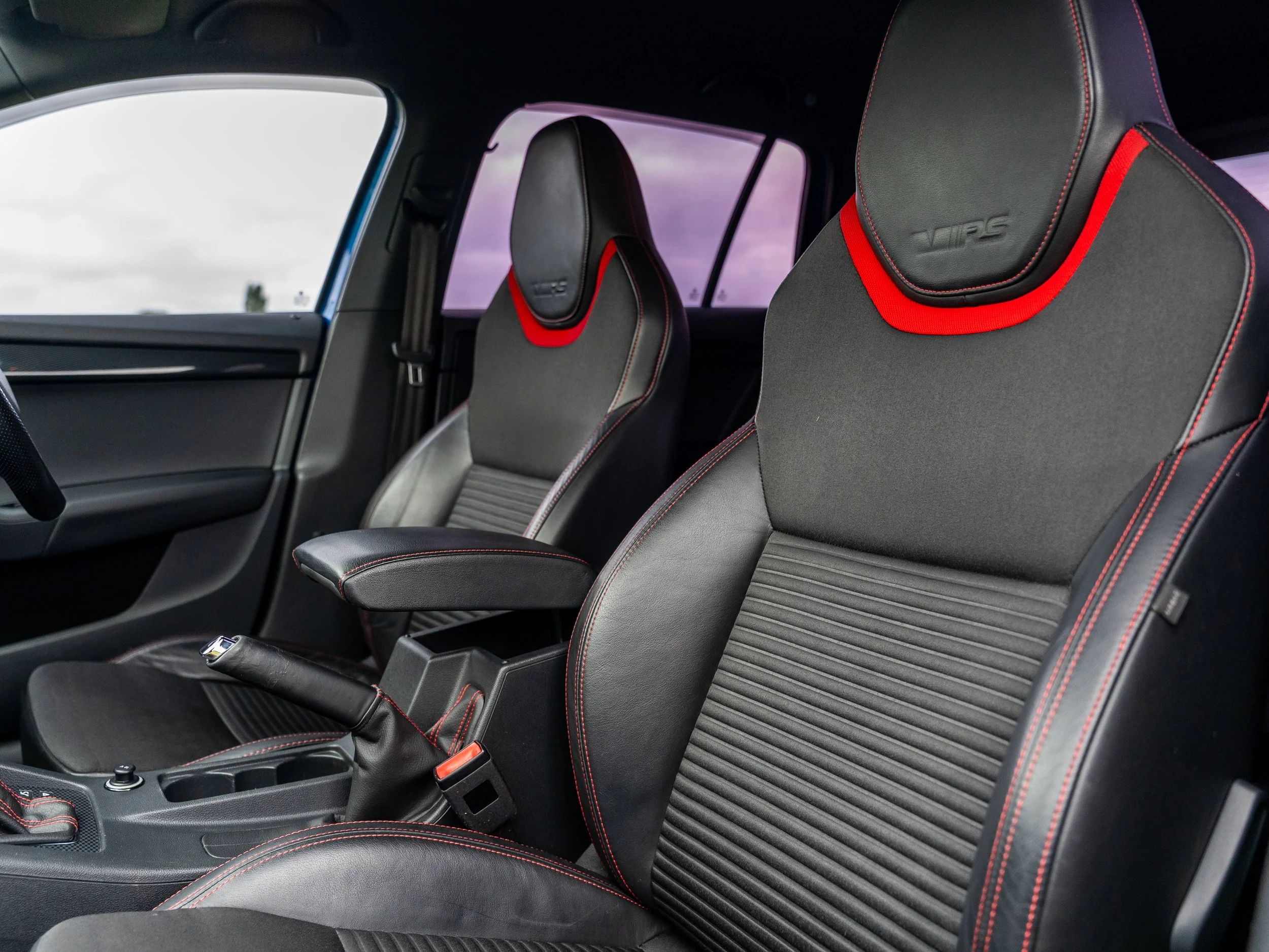 Close-up of the front seats in a car interior, featuring black upholstery with red stitching and headrest accents.