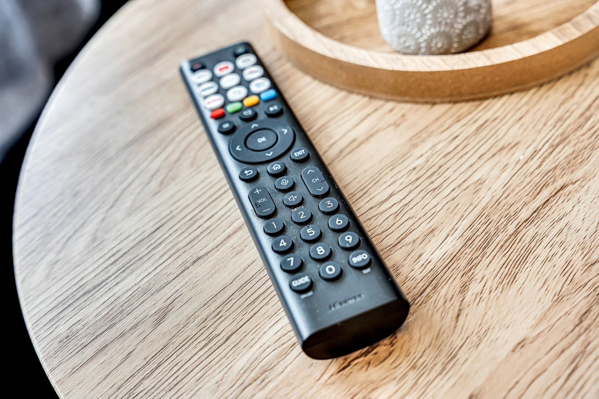Black TV remote control placed on a wooden table.