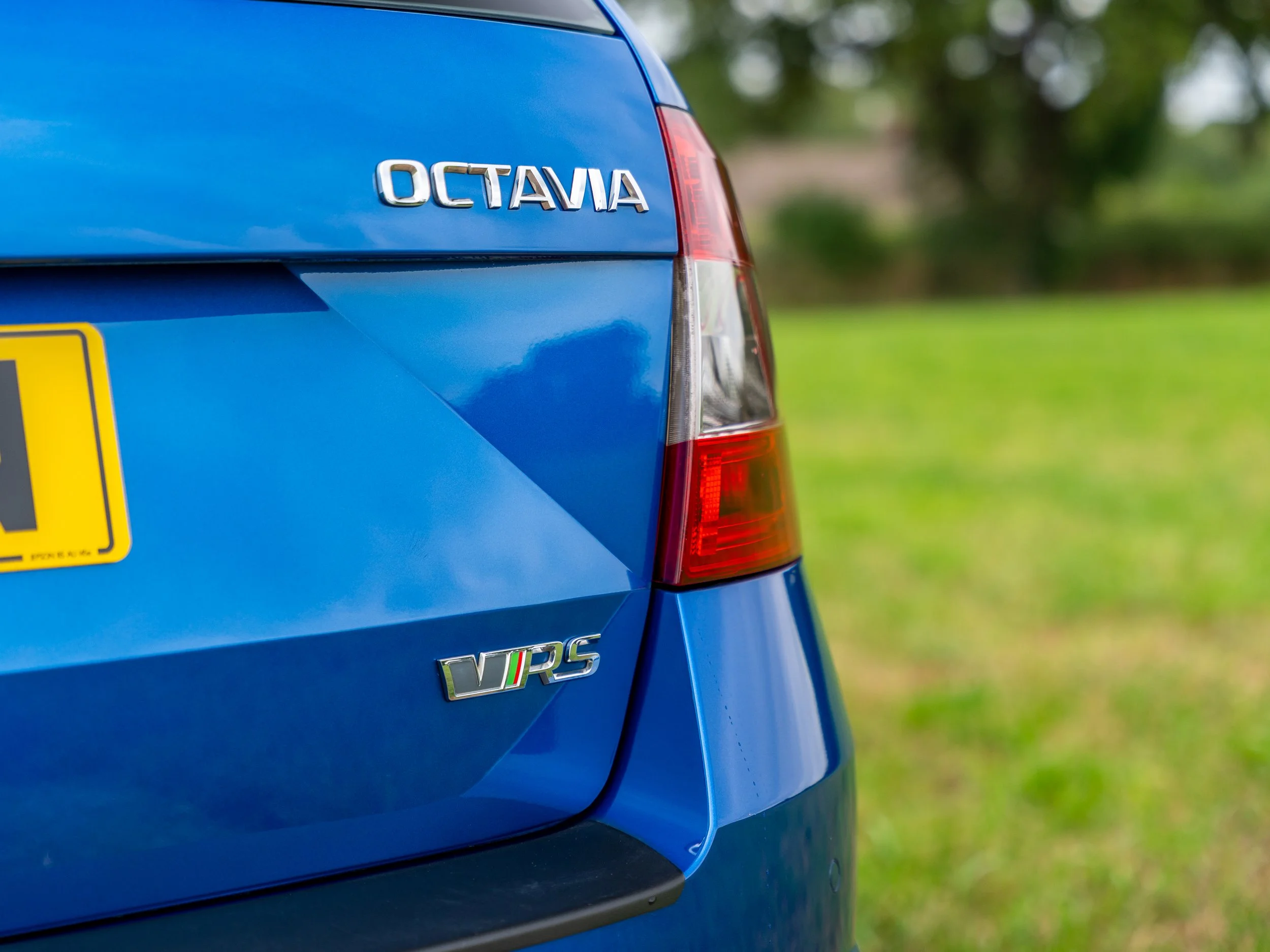 Close-up of the rear of a blue Skoda Octavia car, showing the model badge and VRS badge with an Italian flag detail.