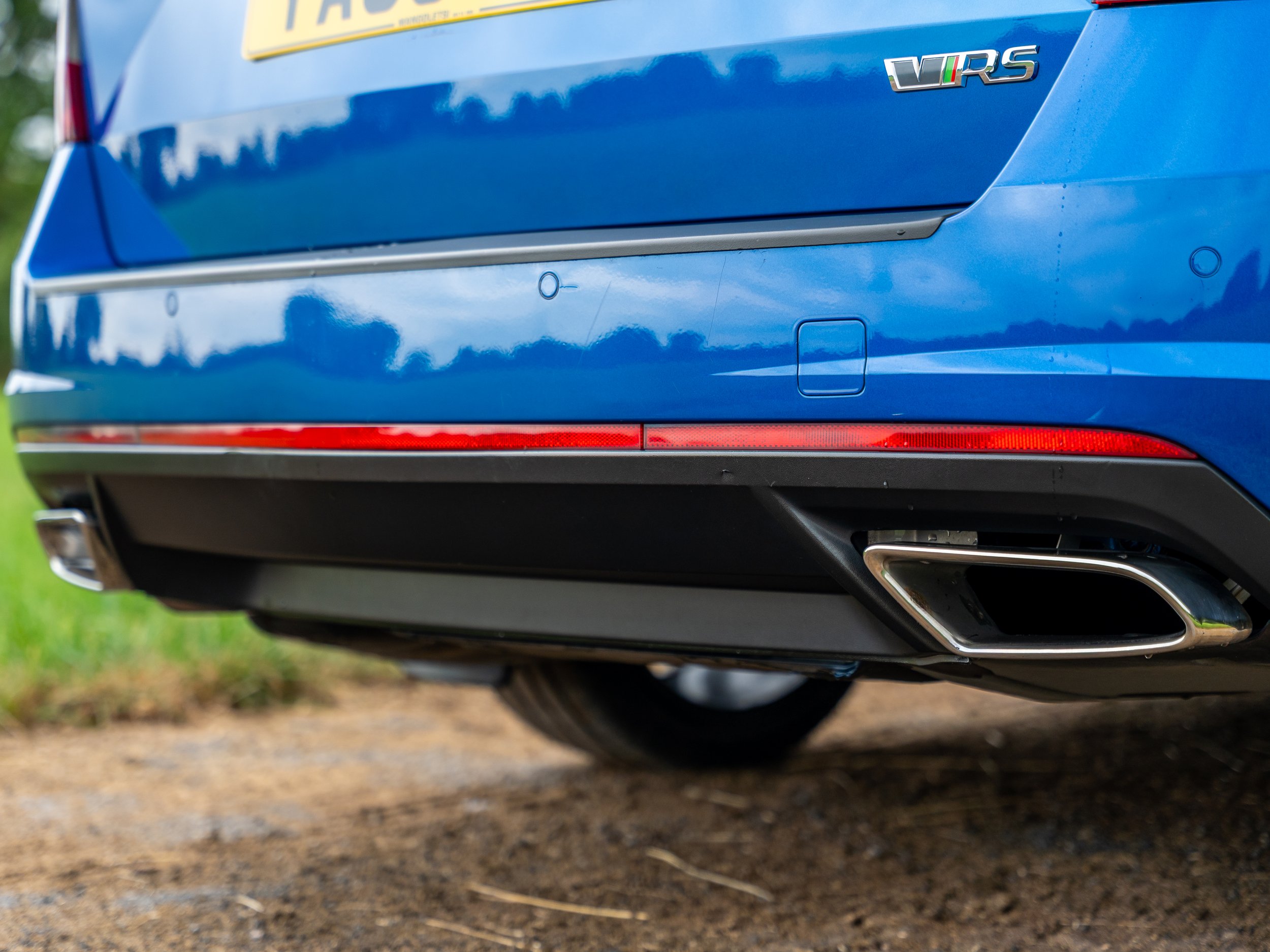 Close-up of the rear end of a blue Volkswagen VR6 vehicle, showing the exhaust pipe, taillight, and rear badge.