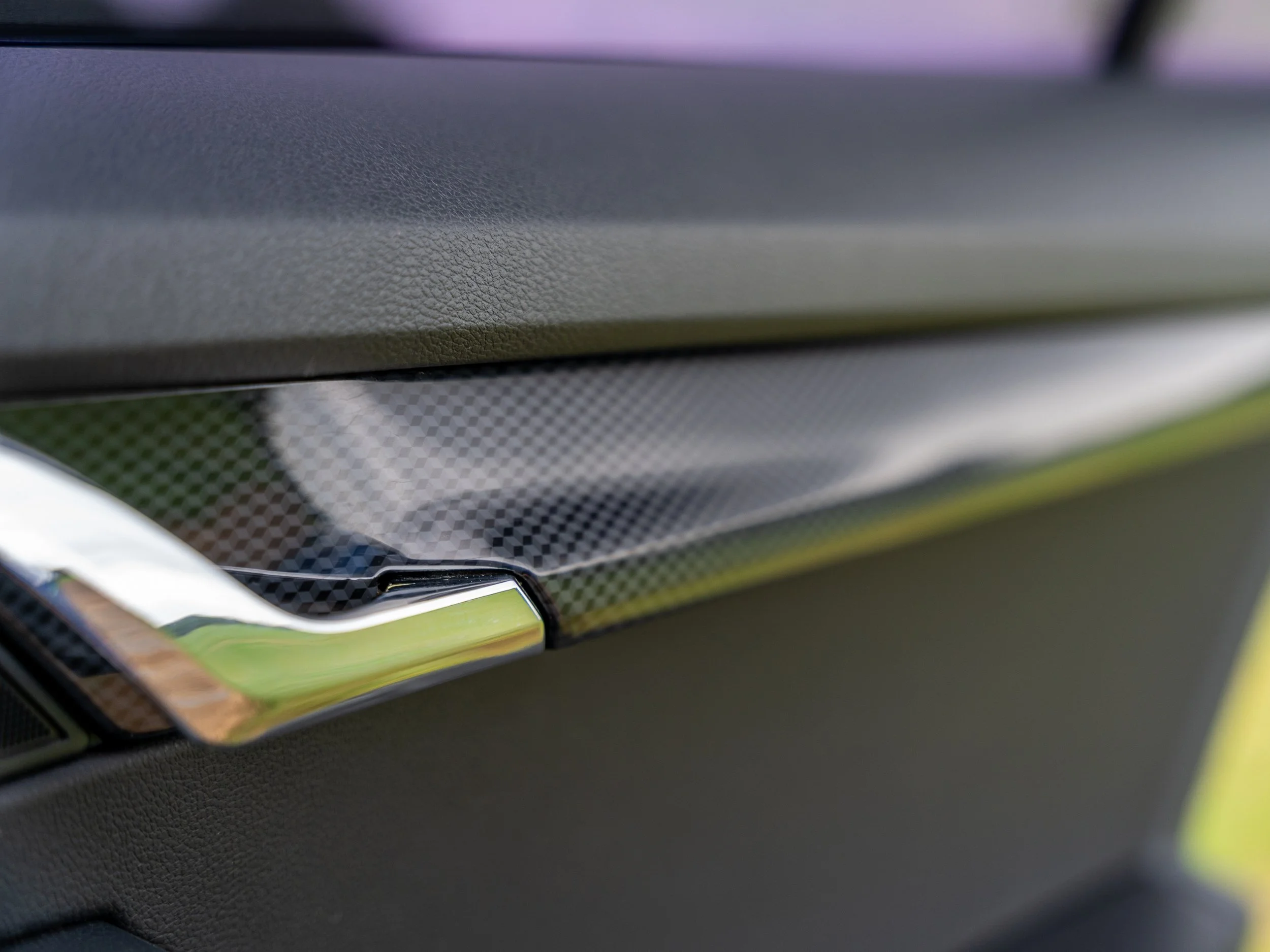 Close-up of a textured black surface with a metallic accent, possibly part of a vehicle interior or electronic device.