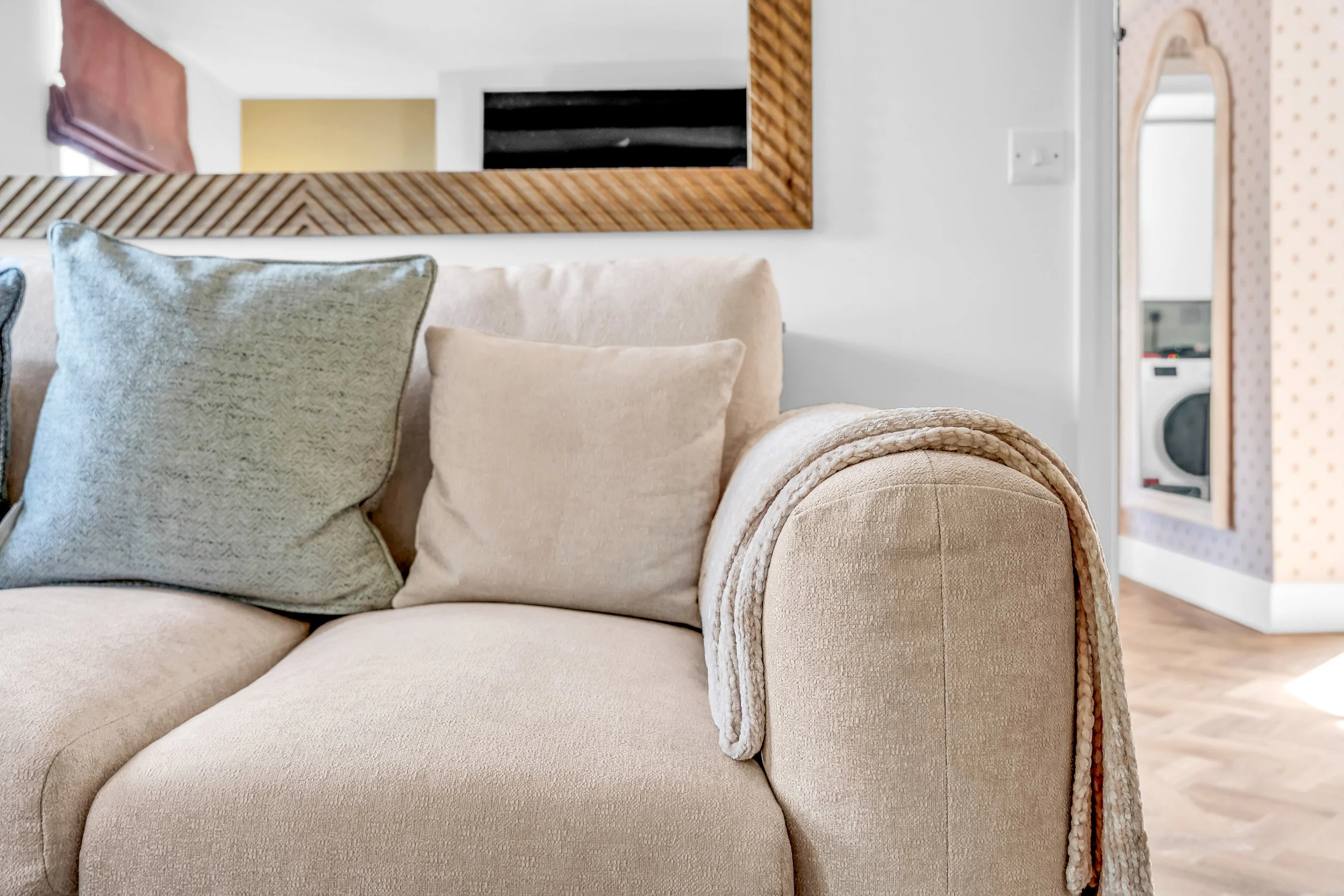 A beige upholstered sofa with rolled arms and plush cushions in a living room.