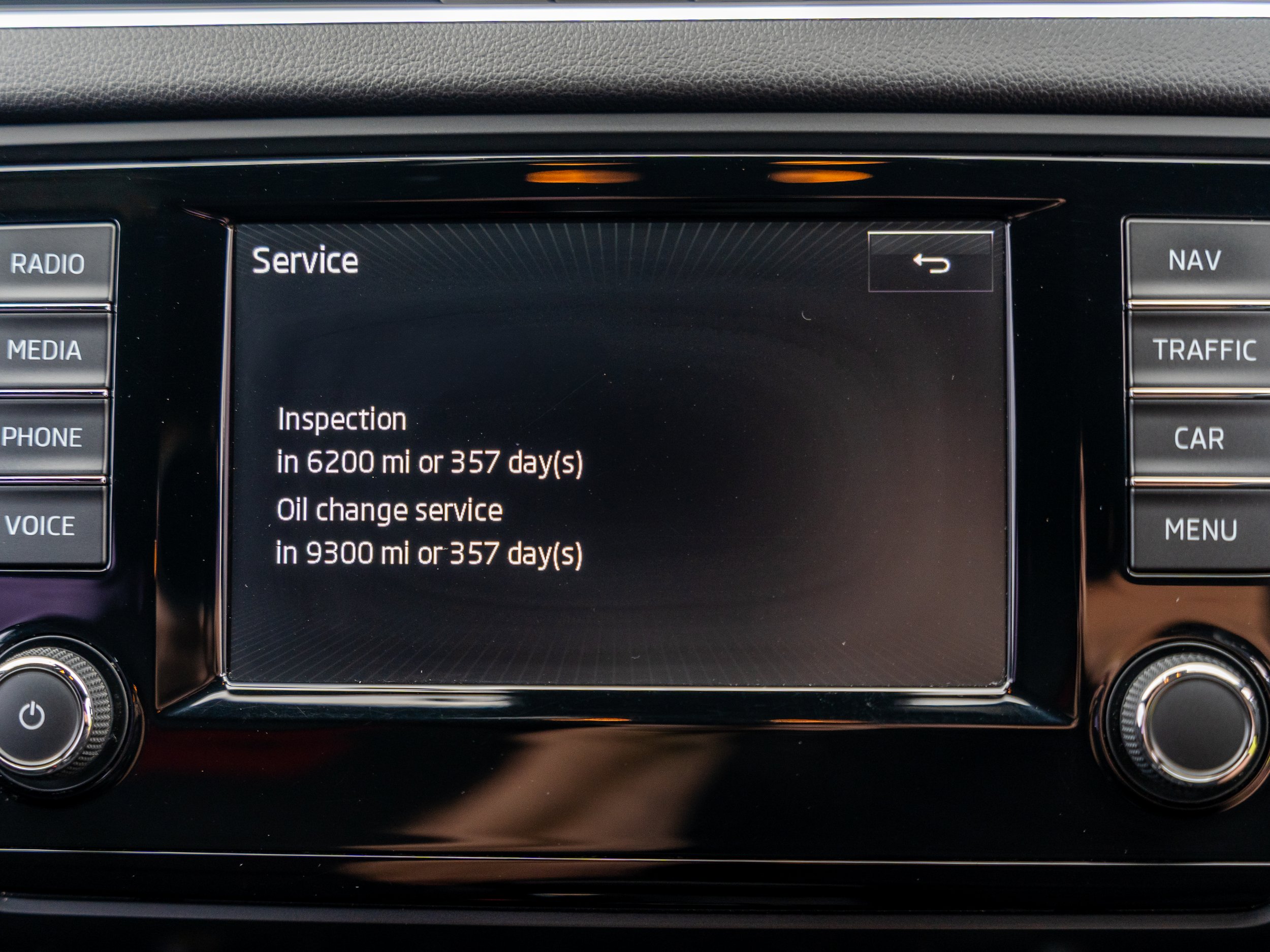 Car infotainment screen displaying service schedule, including inspection in 6200 miles or 357 days, and oil change in 9300 miles or 357 days.