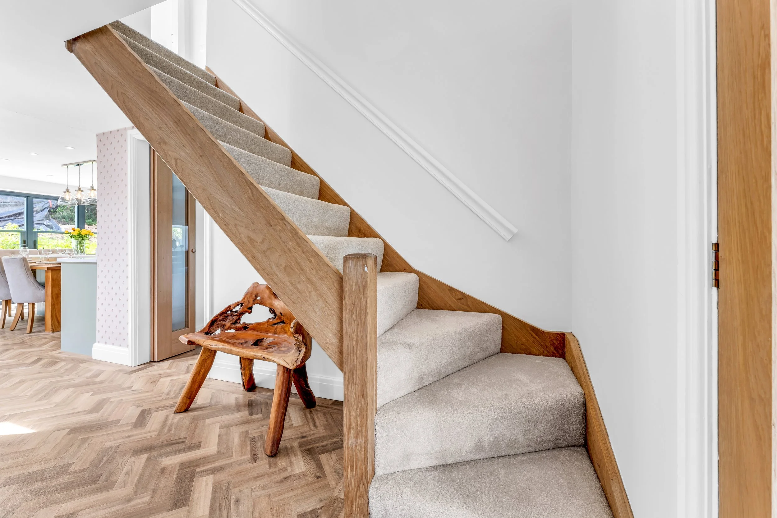 A staircase with beige carpeted steps and wooden side panels leading up to an upper floor in a modern home interior.