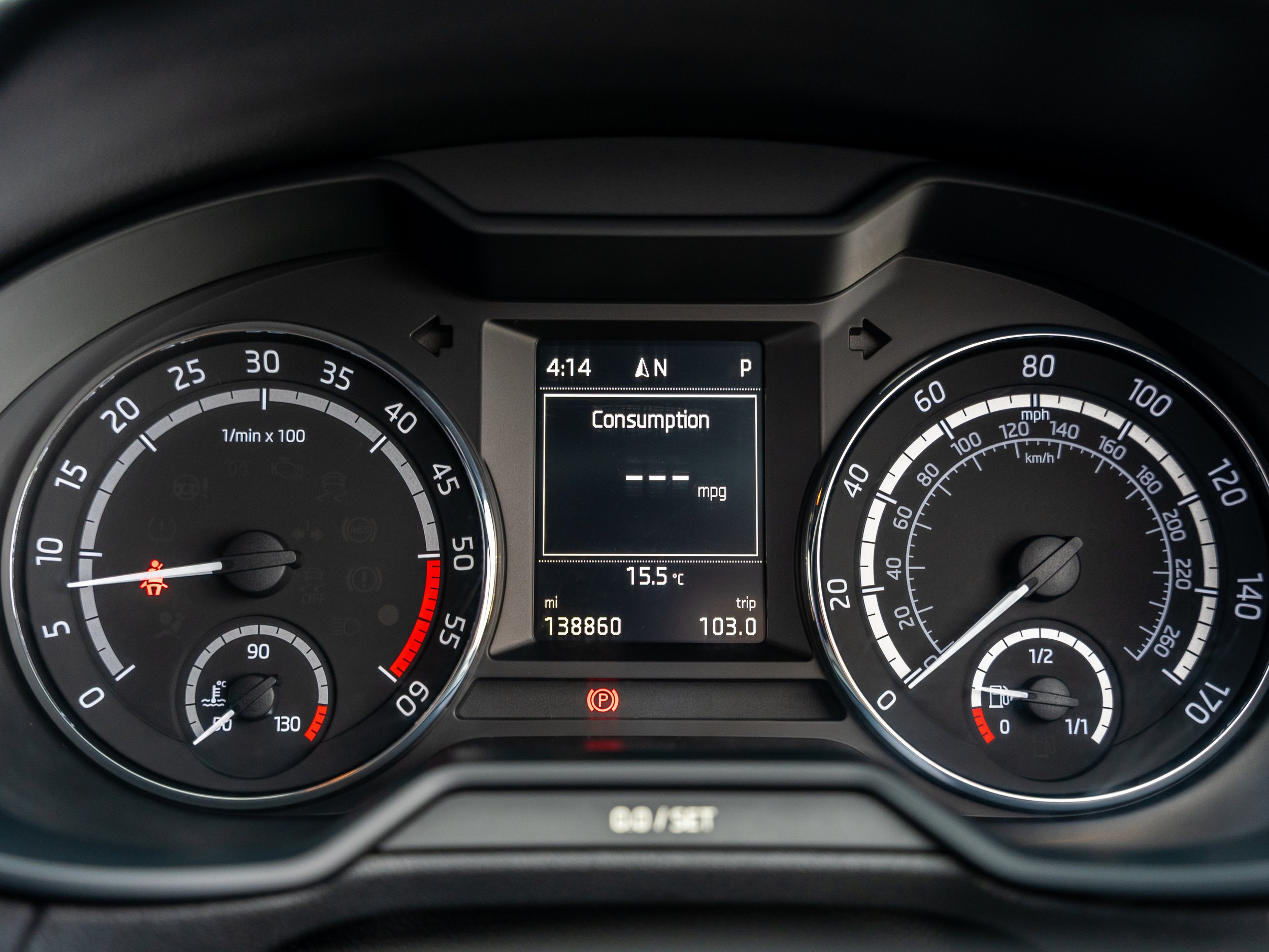 Close-up of a car dashboard showing speedometer, tachometer, fuel gauge, temperature gauge, and digital display with various indicators.