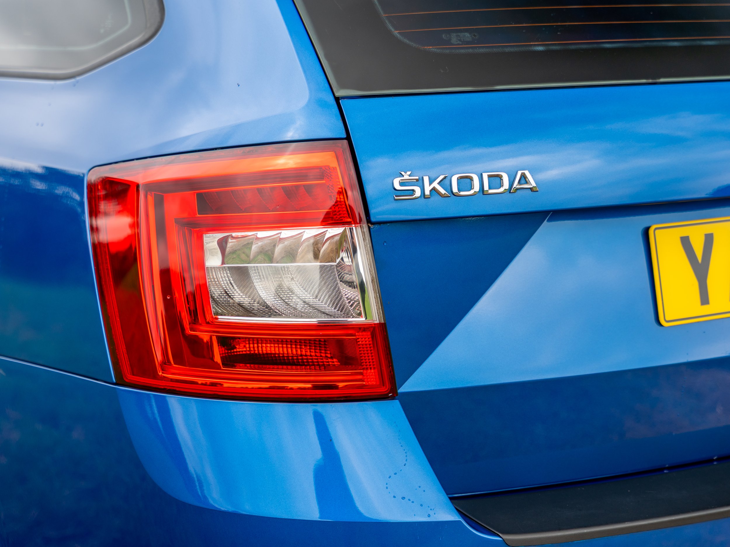 Close-up of the rear of a blue Škoda car, showing the tail light and model badge.