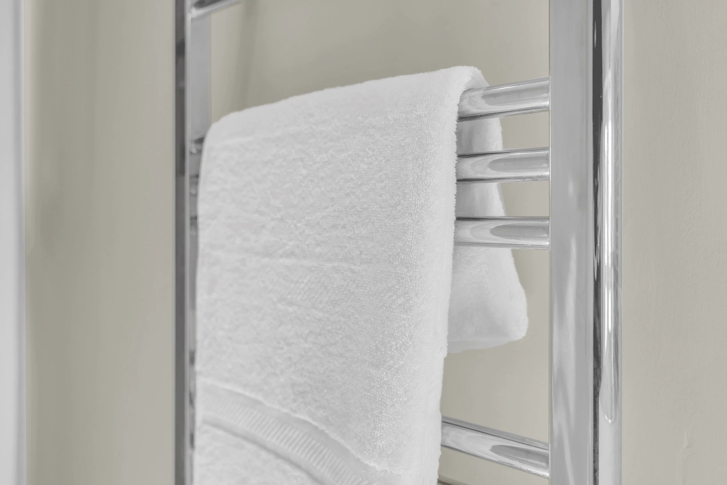 A white towel hanging on a chrome towel rack with LCD tubes.