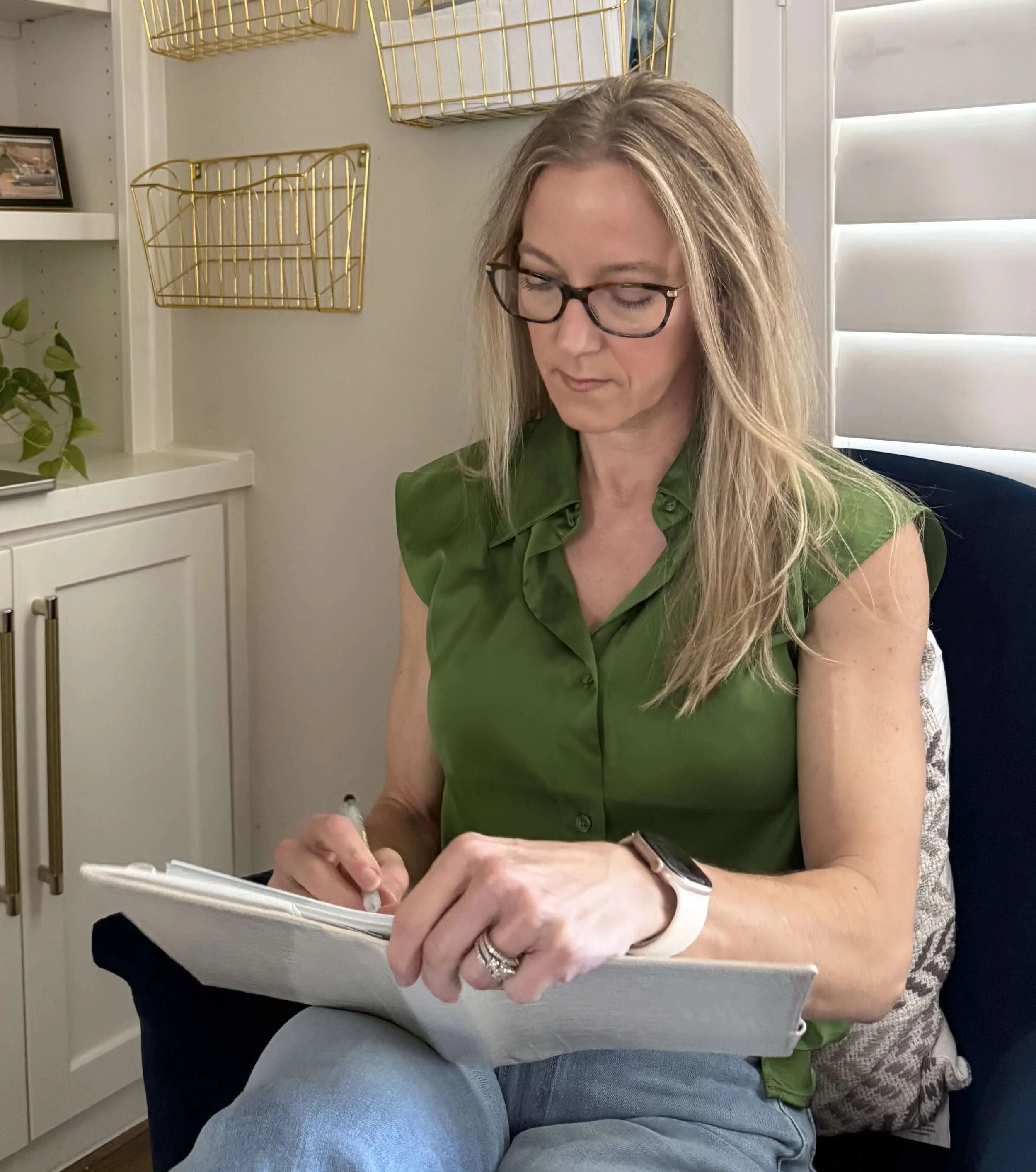 Robin Farley sitting in a chair and writing in her notebook.