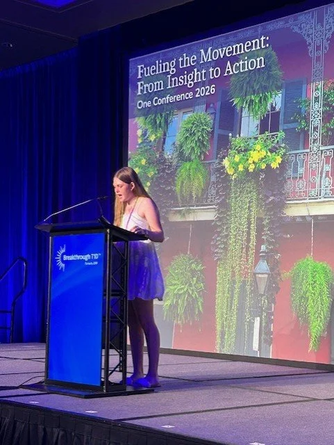 A woman presenting in front of audience at a conference.