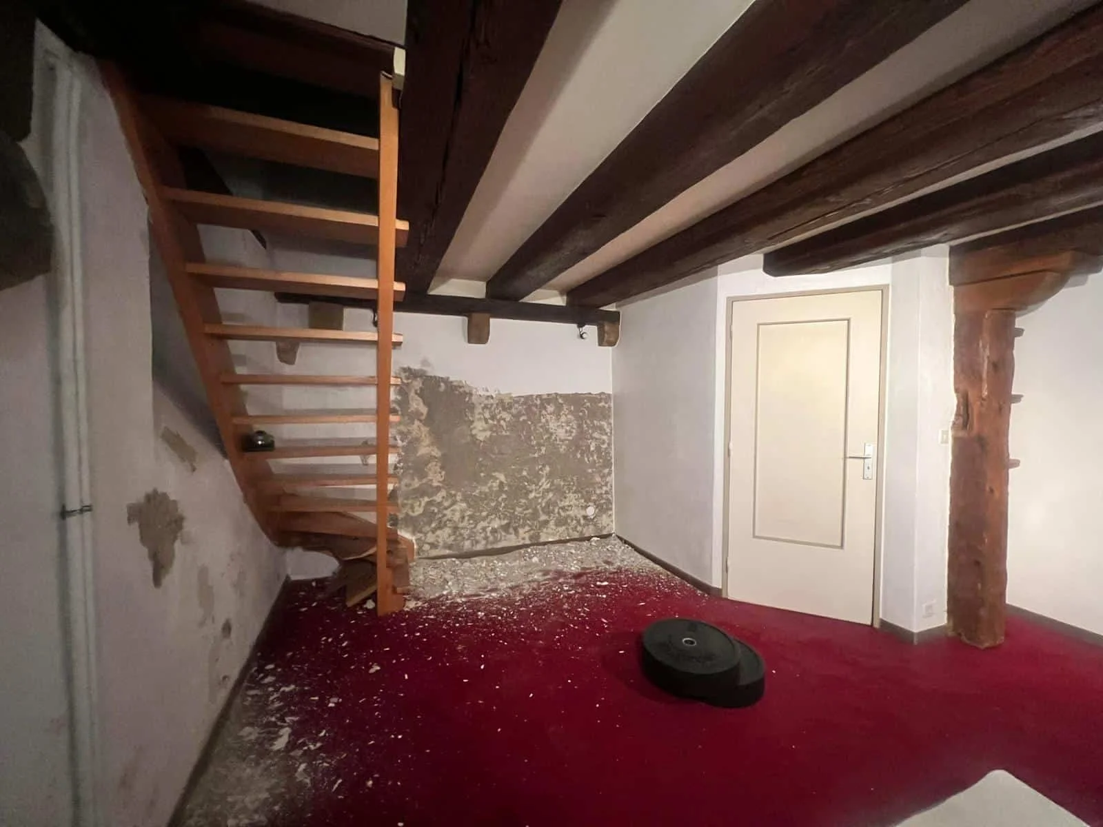 État avant travaux d'un espace en souplex à Genève, révélant de magnifiques poutres apparentes sombres et de beaux volumes à exploiter.