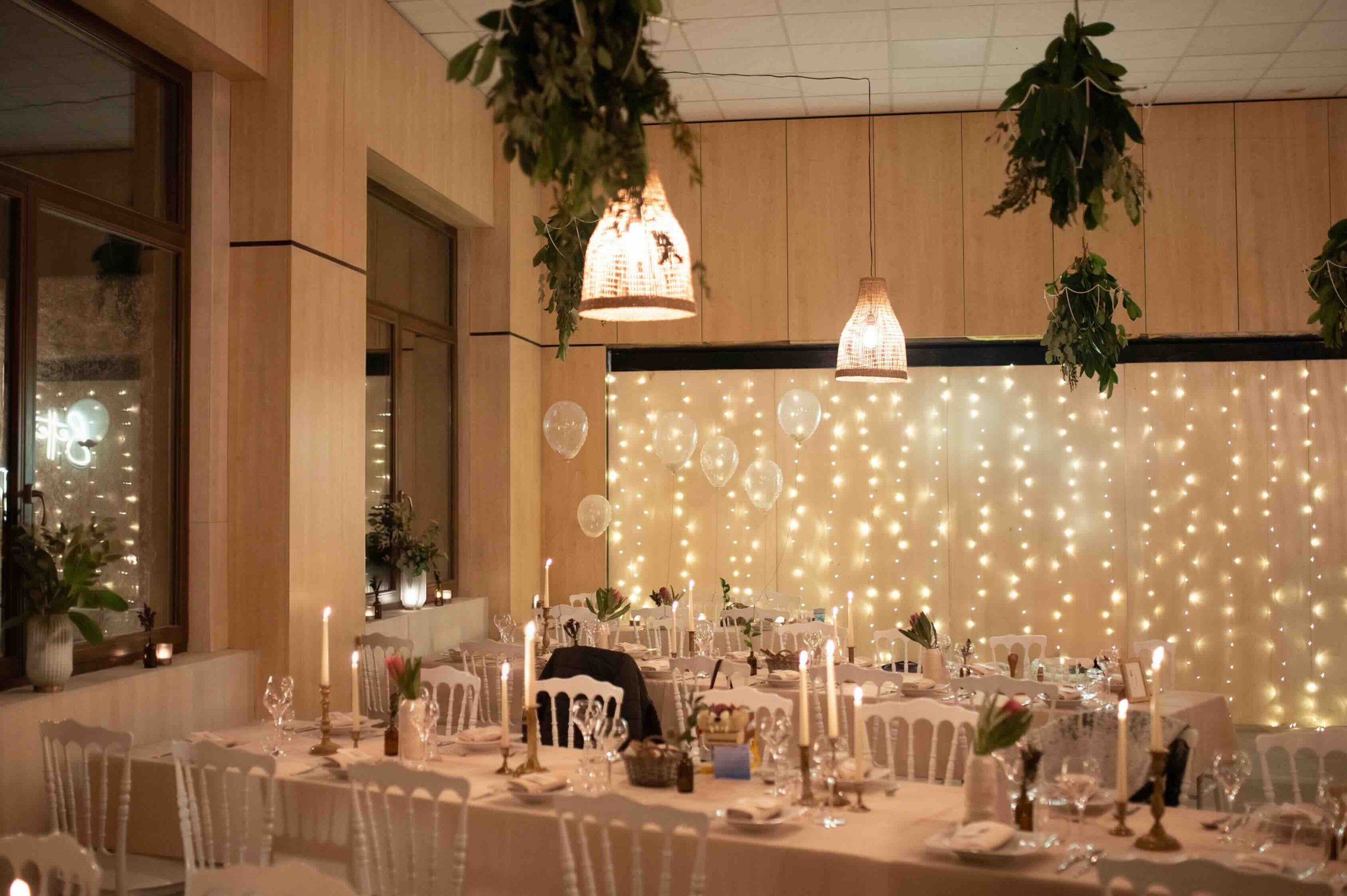 Design d'intérieur d'une salle de réception à Genève avec de longues tables de banquet. Pour adoucir l'ancien volume industriel et repenser l'acoustique, les murs ont été habillés de boiseries blondes, créant une atmosphère chaleureuse et élégante