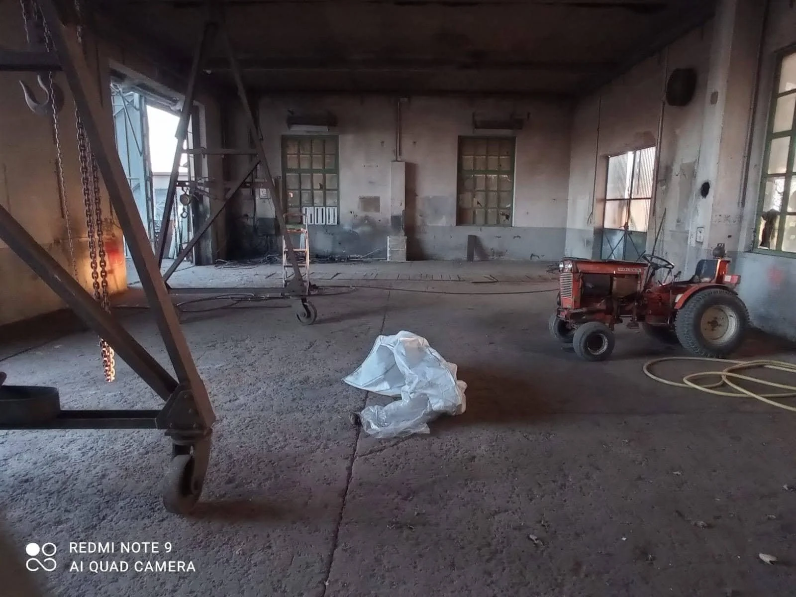 Vaste espace intérieur industriel brut et insalubre avec sol en béton et murs dénudés, illustrant l'état des lieux avant la transformation en salle de réception. Un défi de rénovation architecturale à Genève. Comment percevez-vous le potentiel caché 