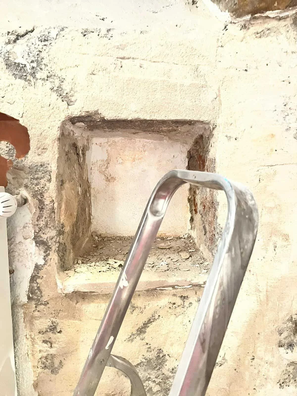 Travaux de démolition et préparation d'une niche murale dans un enduit texturé, une étape clé de la restructuration des espaces de cette appartement à Genève.