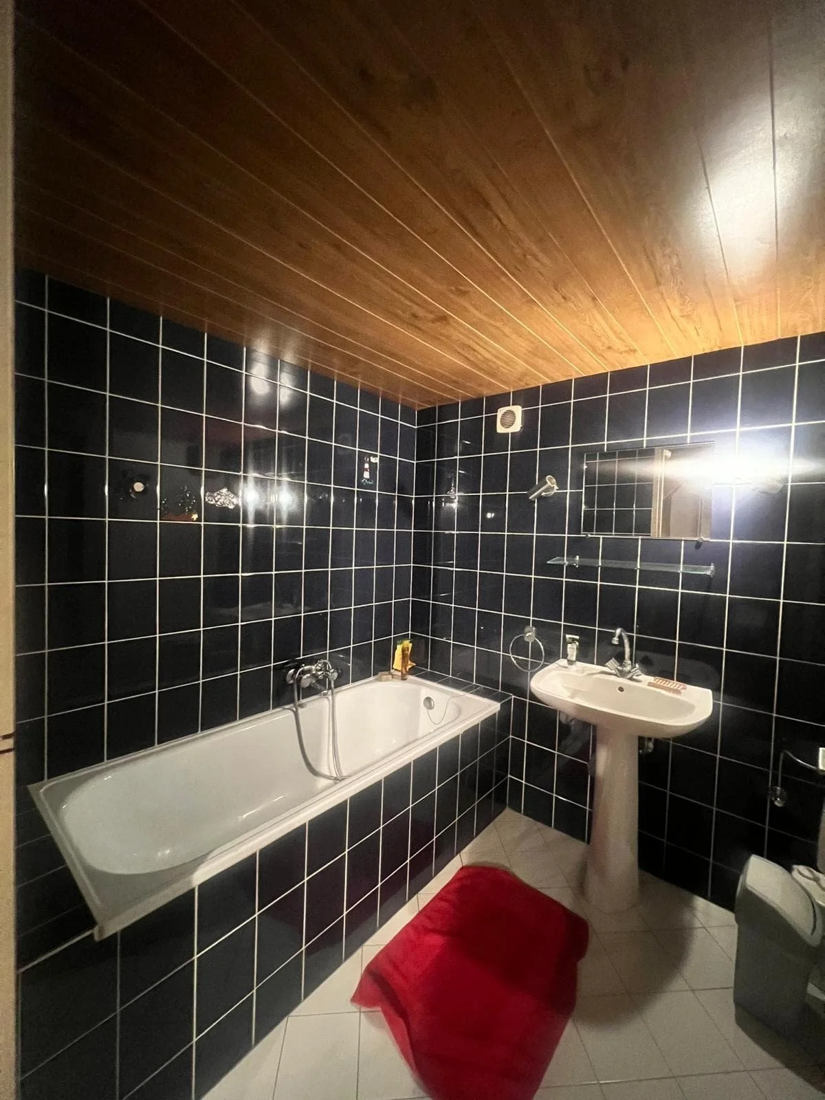 Vue globale de l'ancienne salle de bain avec baignoire, illustrant l'agencement et les matériaux d'origine avant notre intervention de notre bureau d'architecte à Genève.