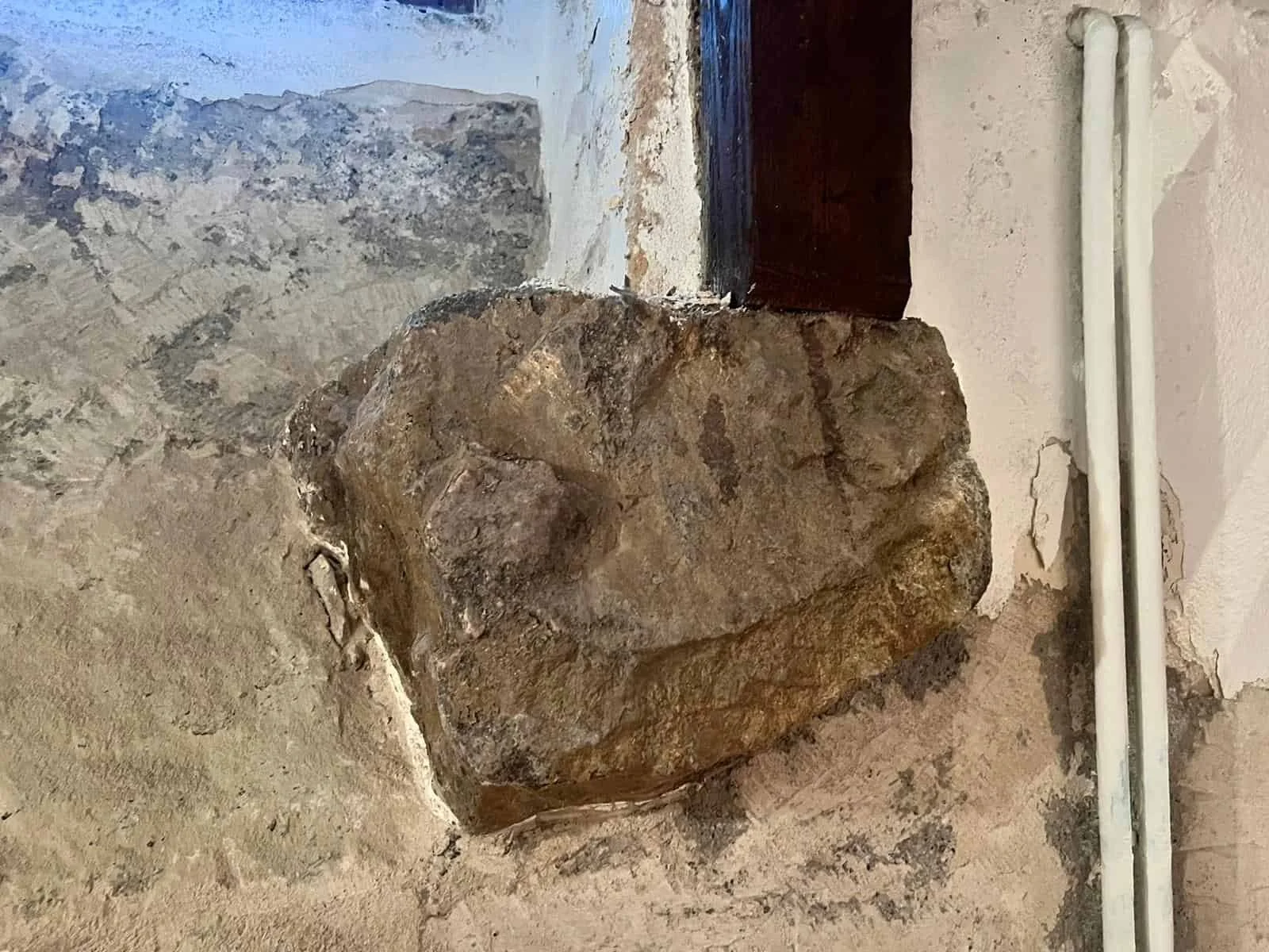 Détail architectural sur un mur en pierre brute mis à nu, soulignant le caractère historique de l'appartement genevois à rénover.