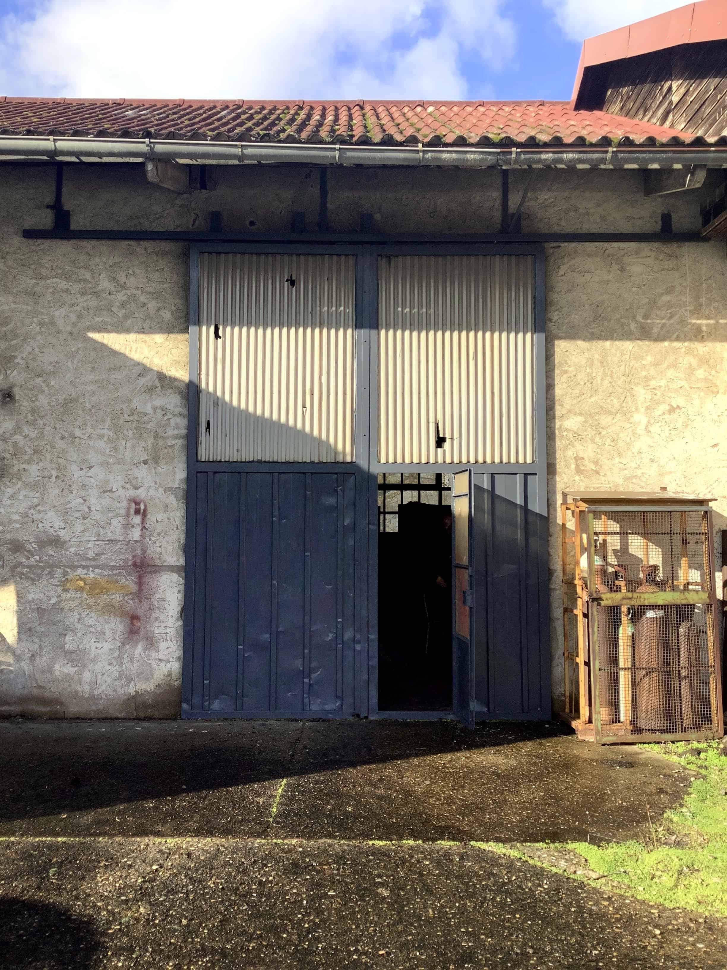 Gros plan sur une double porte de garage métallique bleue intégrée dans un mur aux enduits vieillissants. Ce vestige industriel témoigne de l'histoire du bâtiment avant son changement d'affectation. Quels éléments de cette patine ancienne intégreriez