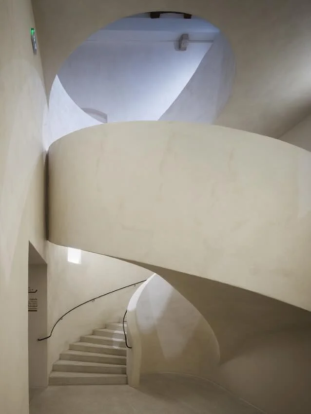 Escalier monumental en colimaçon aux courbes fluides et épurées photographié au Musée Unterlinden. Une source d'inspiration architecturale majeure qui guide la conception d'espaces intérieurs sculpturaux et sur mesure par notre bureau.