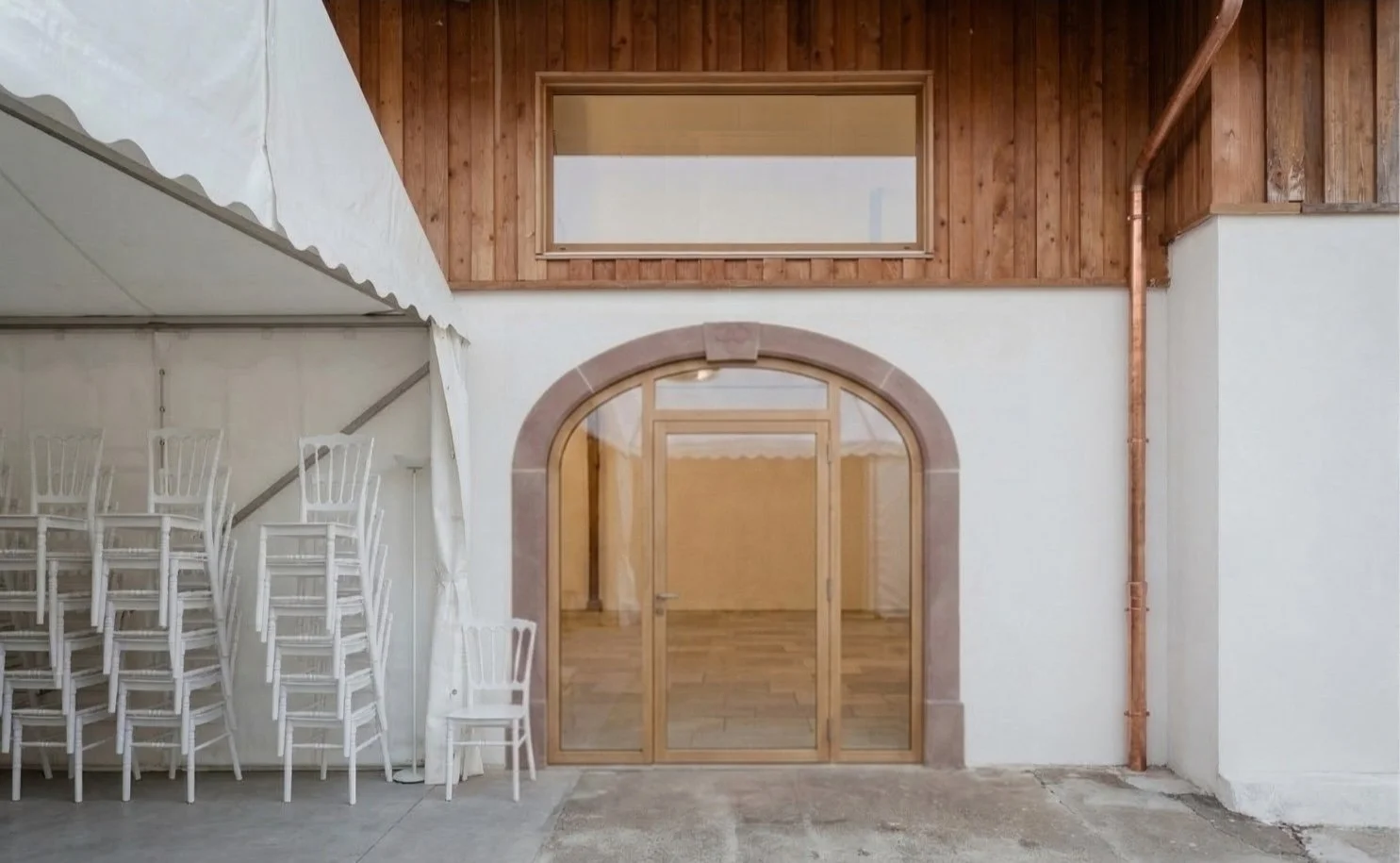 Vue sur l'entrée de la salle de réception mettant en valeur une arche en grès des Vosges taillée sur mesure. L'utilisation de cette pierre issue d'une carrière locale souligne l'approche éco-responsable de cette rénovation genevoise.