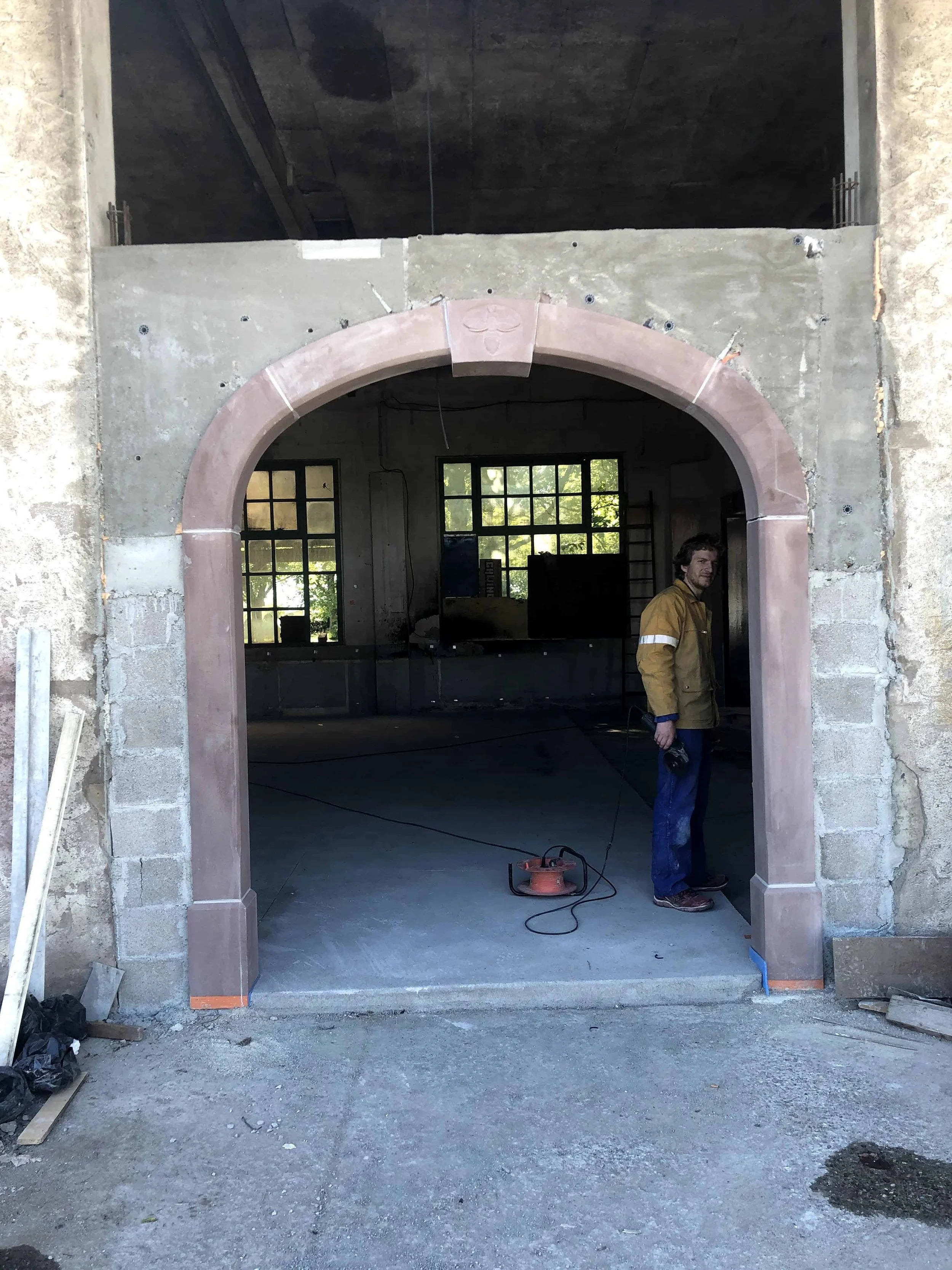 Arche en pierre de taille parfaitement exécutée, encadrant une large ouverture vers un espace intérieur désormais dégagé et lumineux. Contraste saisissant entre les matériaux traditionnels et la nouvelle fonction événementielle du lieu. Que pensez-vo
