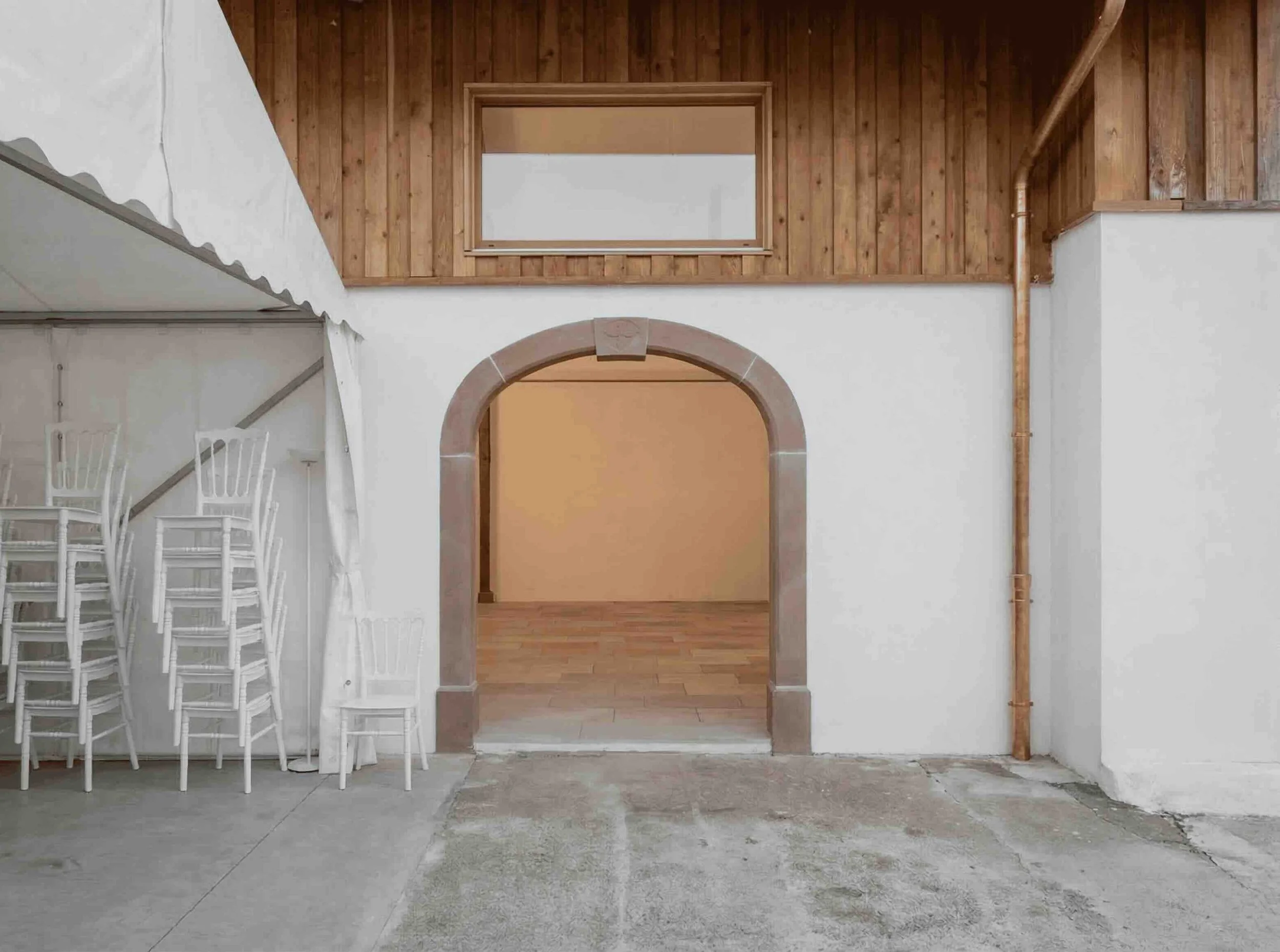 Vue sur l'entrée de la salle de réception mettant en valeur une arche en grès des Vosges taillée sur mesure. L'utilisation de cette pierre issue d'une carrière locale souligne l'approche éco-responsable de cette rénovation genevoise.