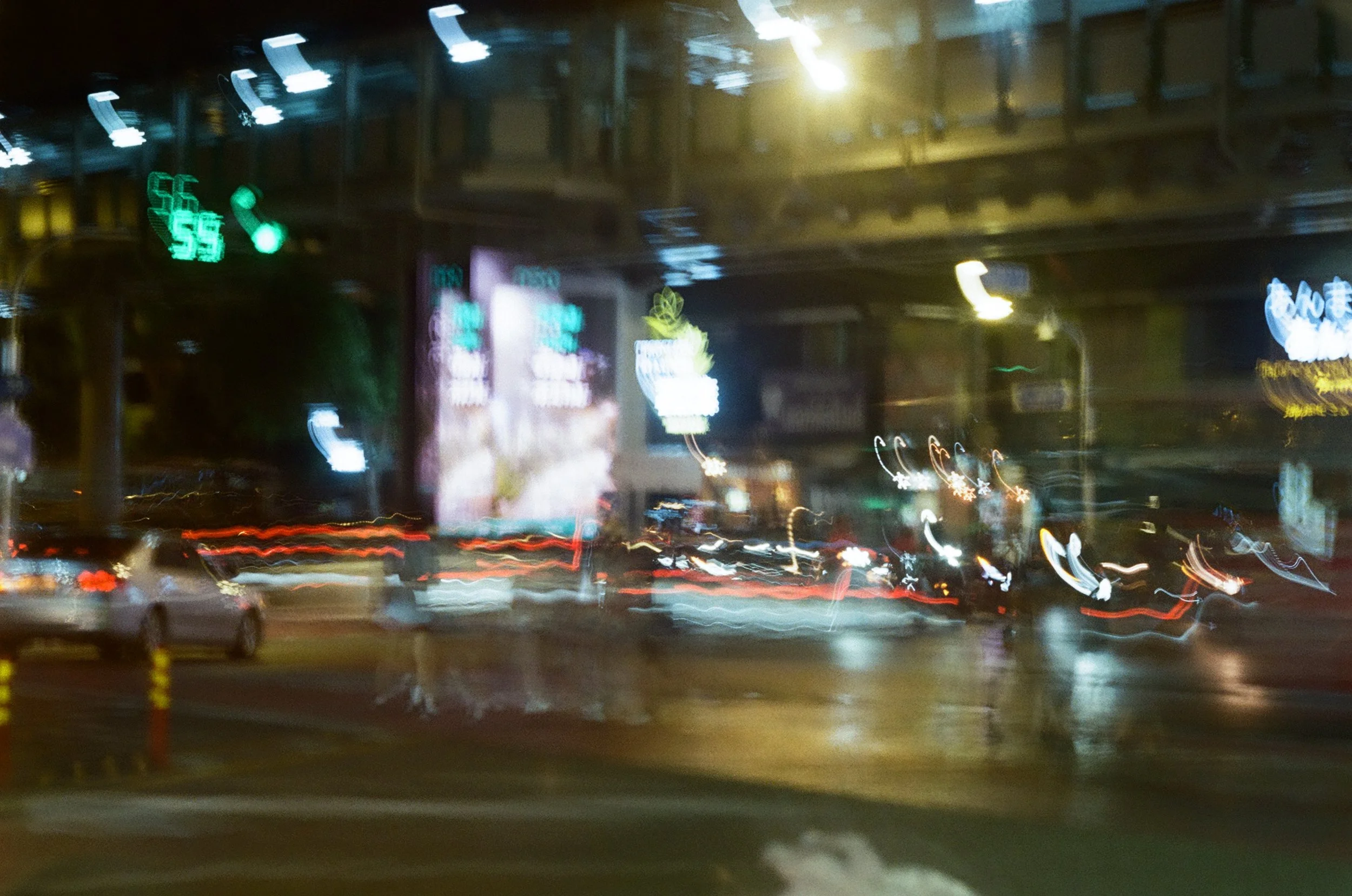 Nighttime city street with blurred moving lights, cars, and illuminated signs.
