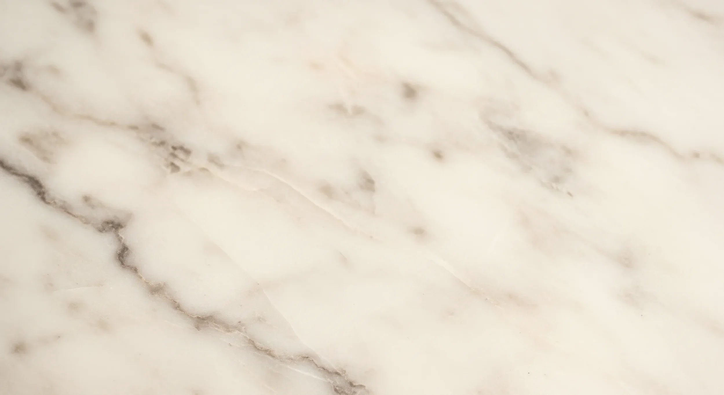Close-up view of a marble surface with white, cream, and light brown veining.