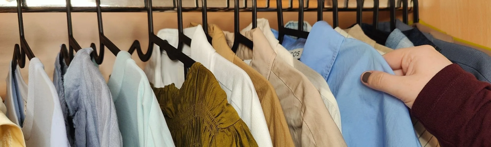 organised clothes hanging in a wardrobe in a muted colour palette