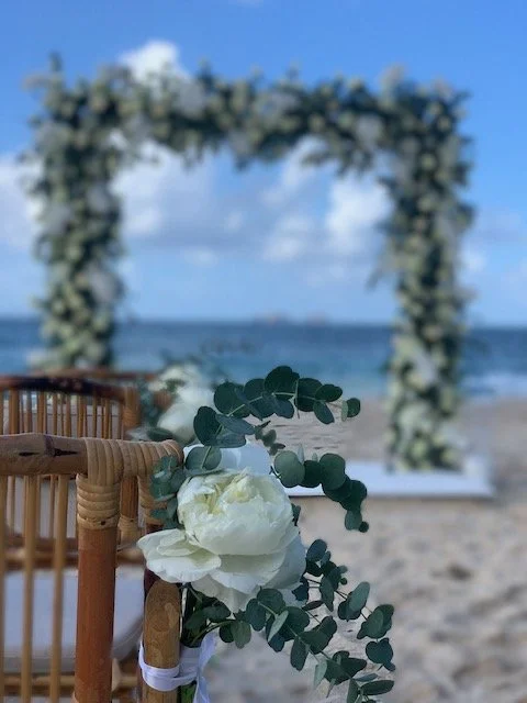 Décoration de mariage sur la plage avec un arche florale en arrière-plan