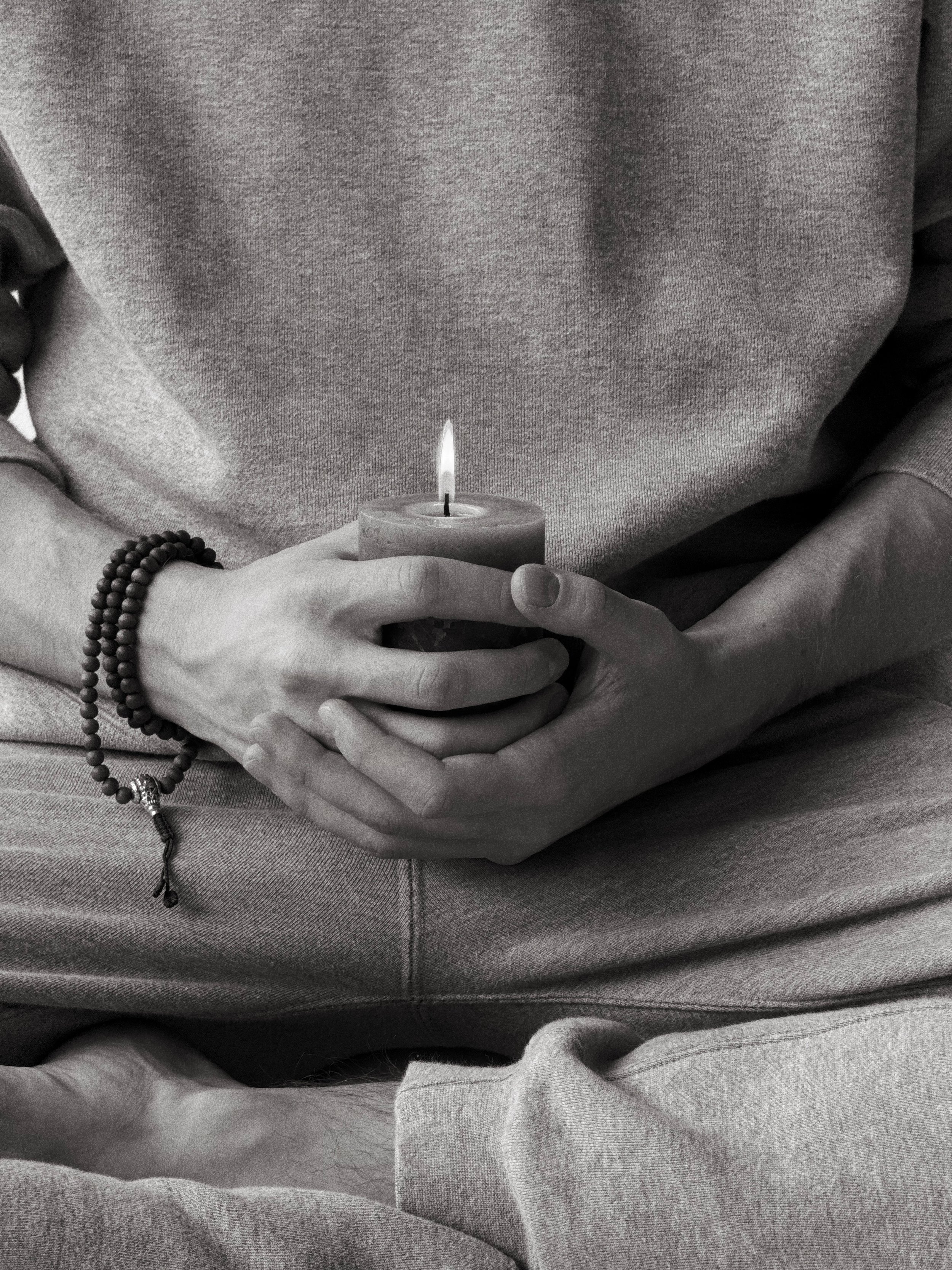 Meditace – ruce držící zapálenou svíčku v klidném prostředí