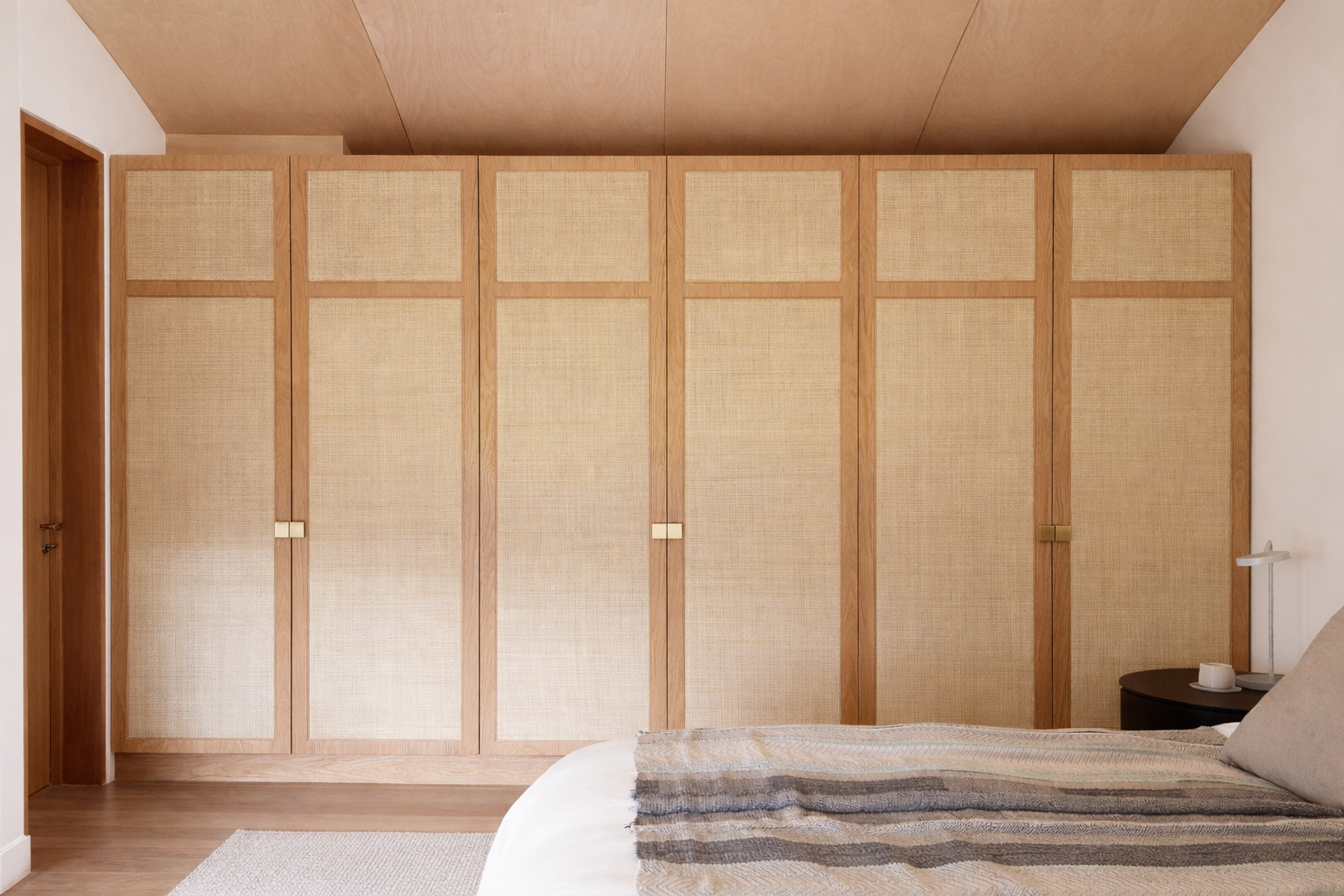 Full wall of fitted bedroom wardrobes with woven panels