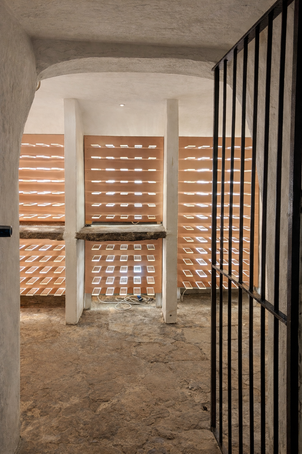 Wine cellar with illuminated bottle shelving and stone floor