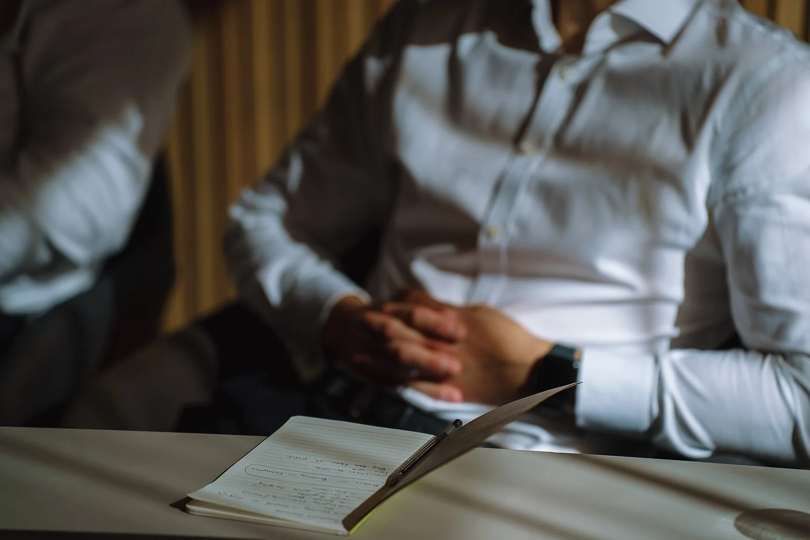 Two people in white shirts sitting at a table with a handwritten notebook