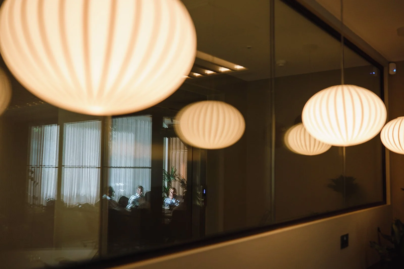 Warm glowing spherical pendant lights reflected in a large mirror inside a dimly lit interior
