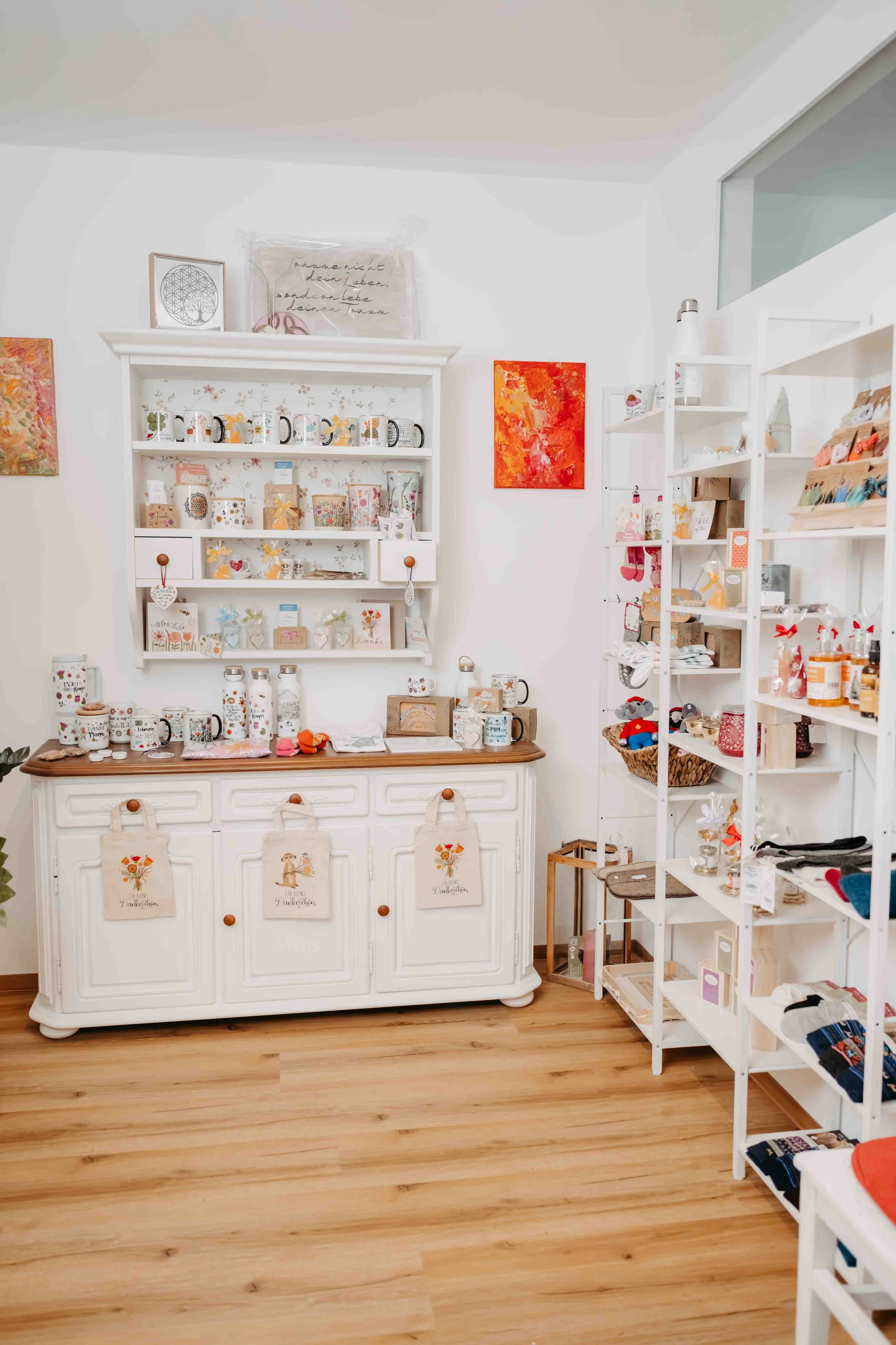 Verkaufsregal mit Keramik- und Geschenkartikeln in einem Geschenk- und Deko-Shop, weiße Möbel, Holzboden.