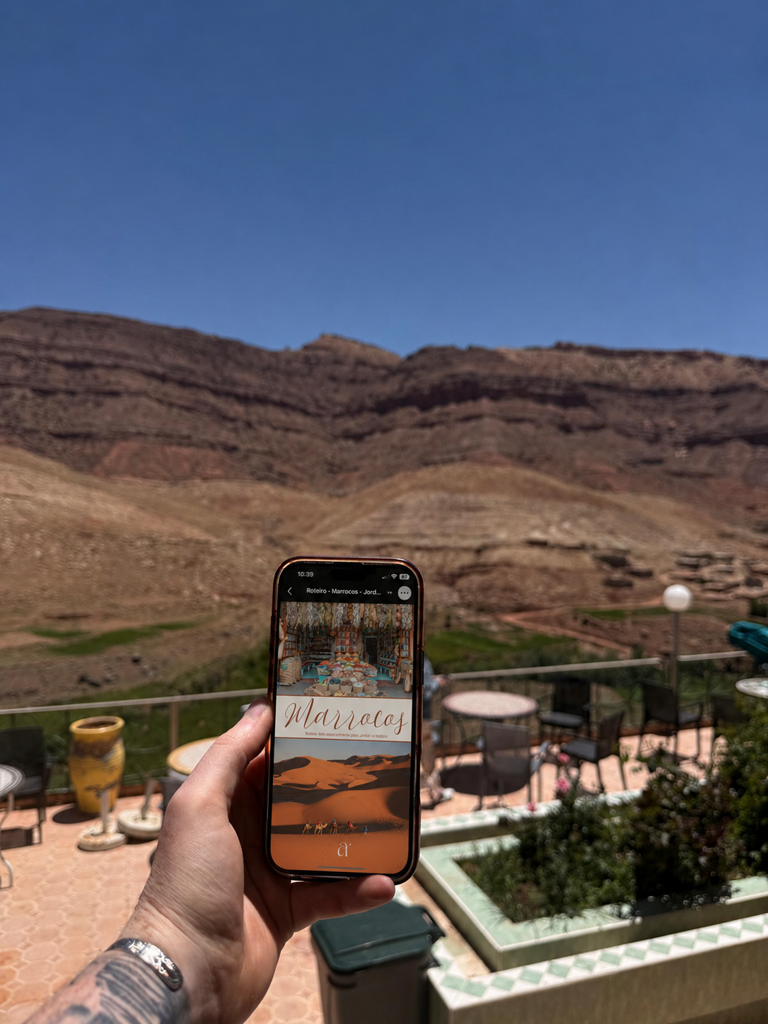 Roteiro digital aberto em um celular com a paisagem de marrocos ao fundo