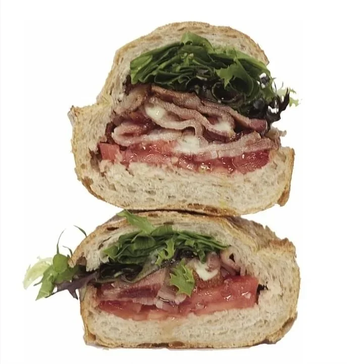 Cross-section of a sandwich with bacon, lettuce, tomato, and cheese on whole wheat bread.