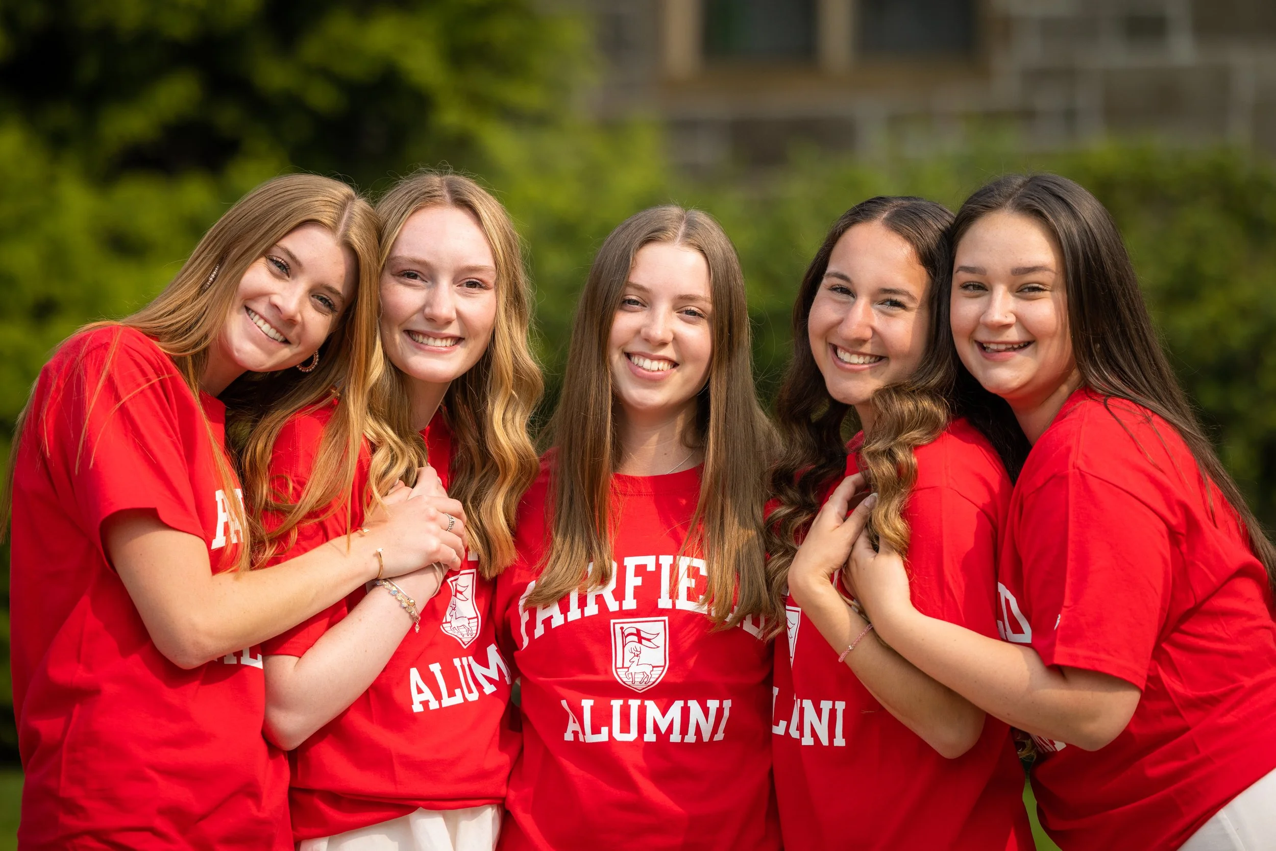 Five graduates from Fairfield College posing in their alumni shirts for a photo