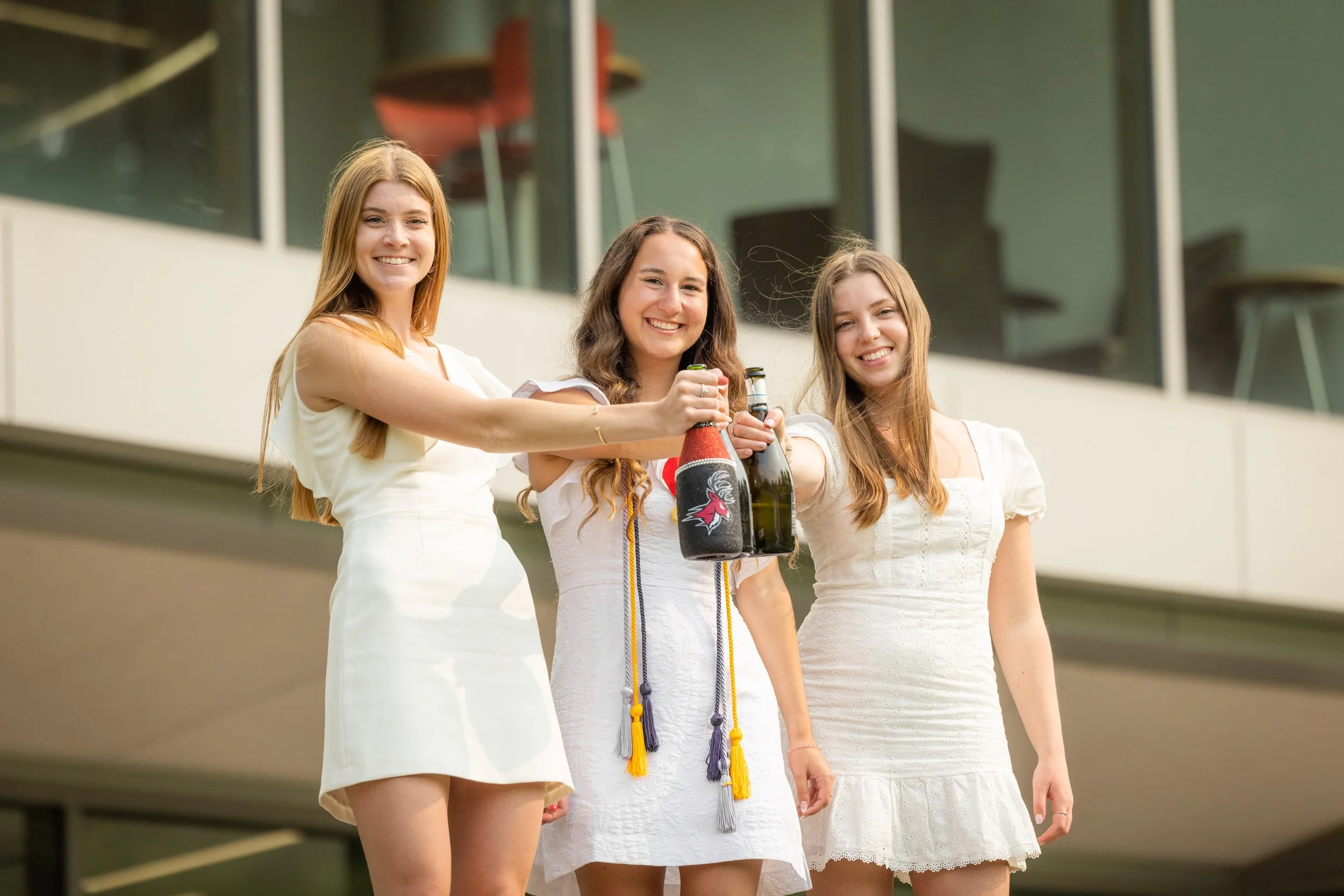 High quality image of three graduates popping champagne
