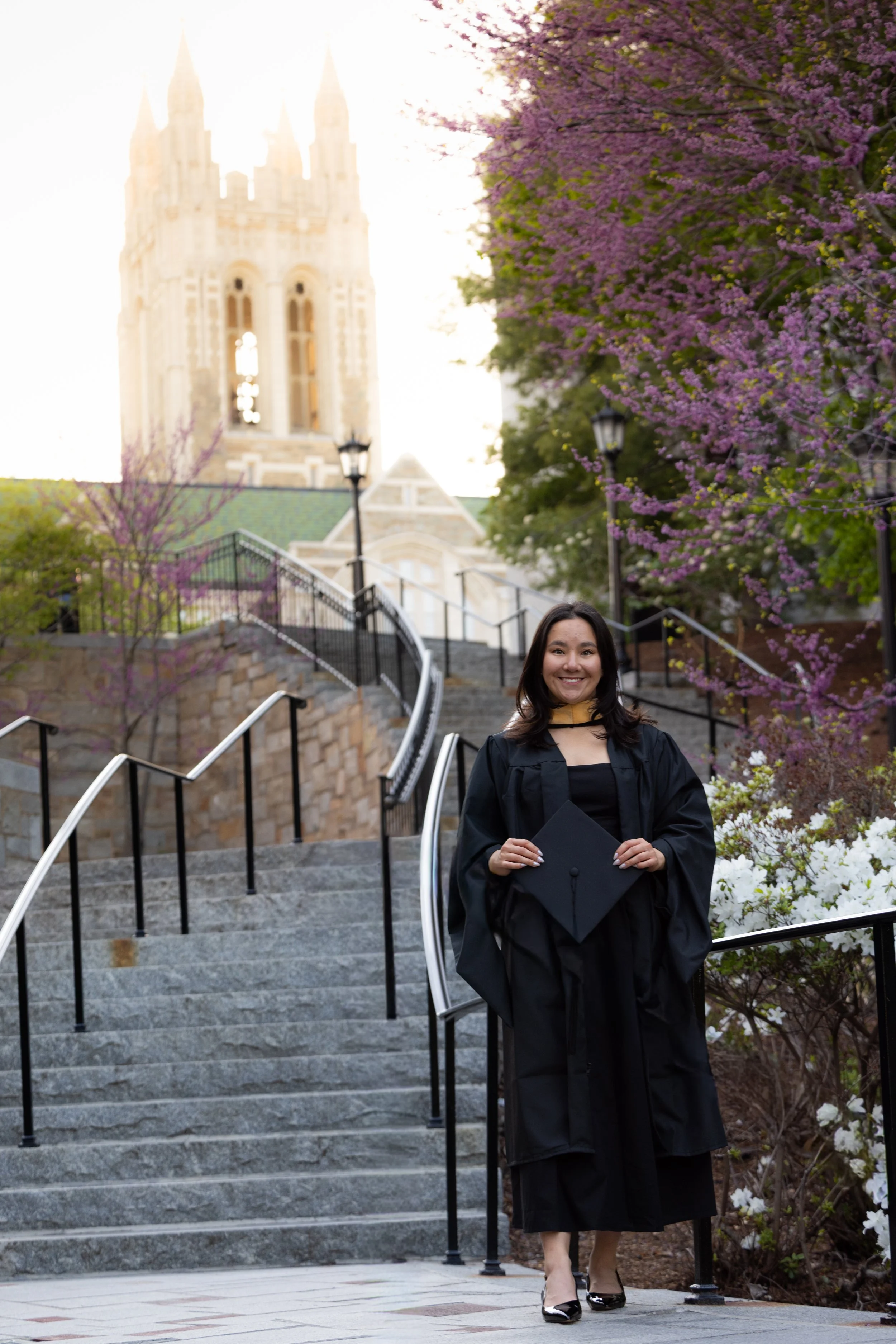 A graduate holding a cap while wearing a graduation gown