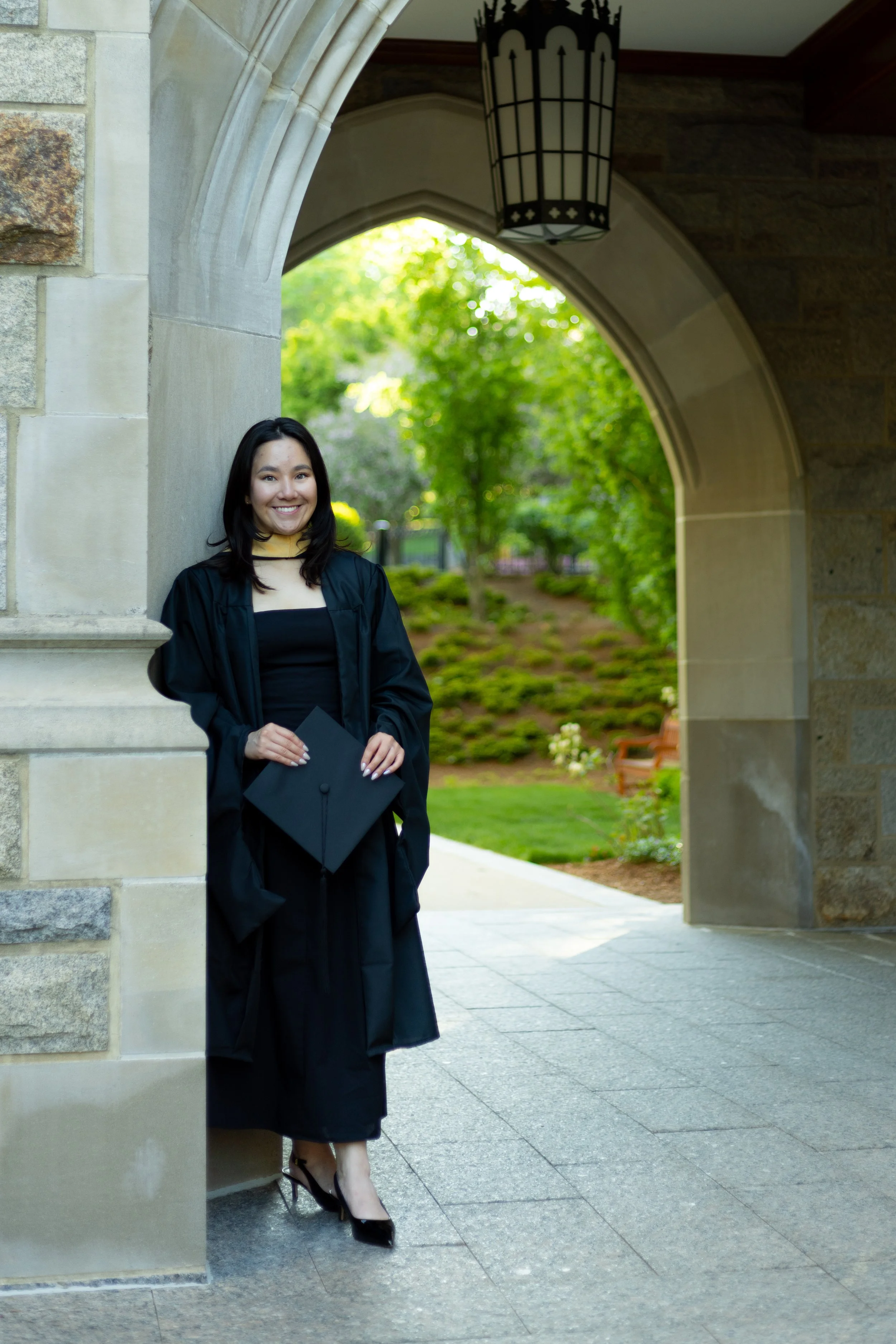 A graduate from Boston College posing in front of an archway