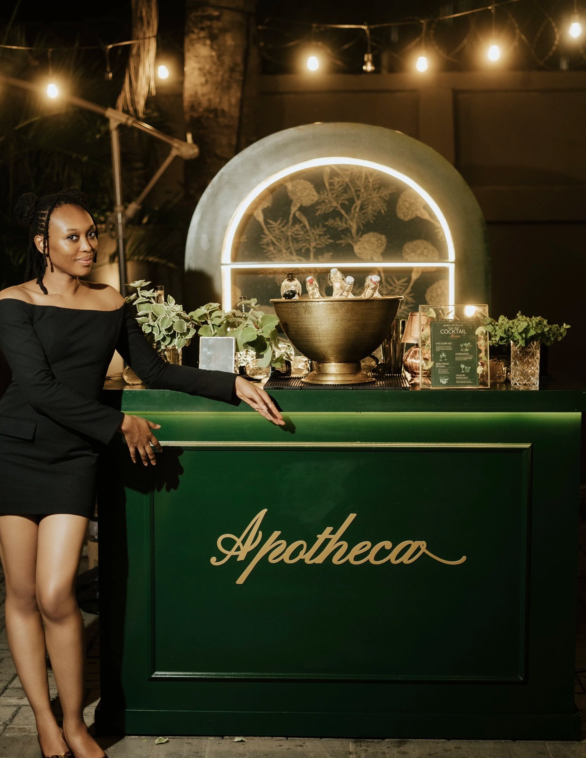 Female bartender posing in front of Apotheca's mobile cocktail bar.
