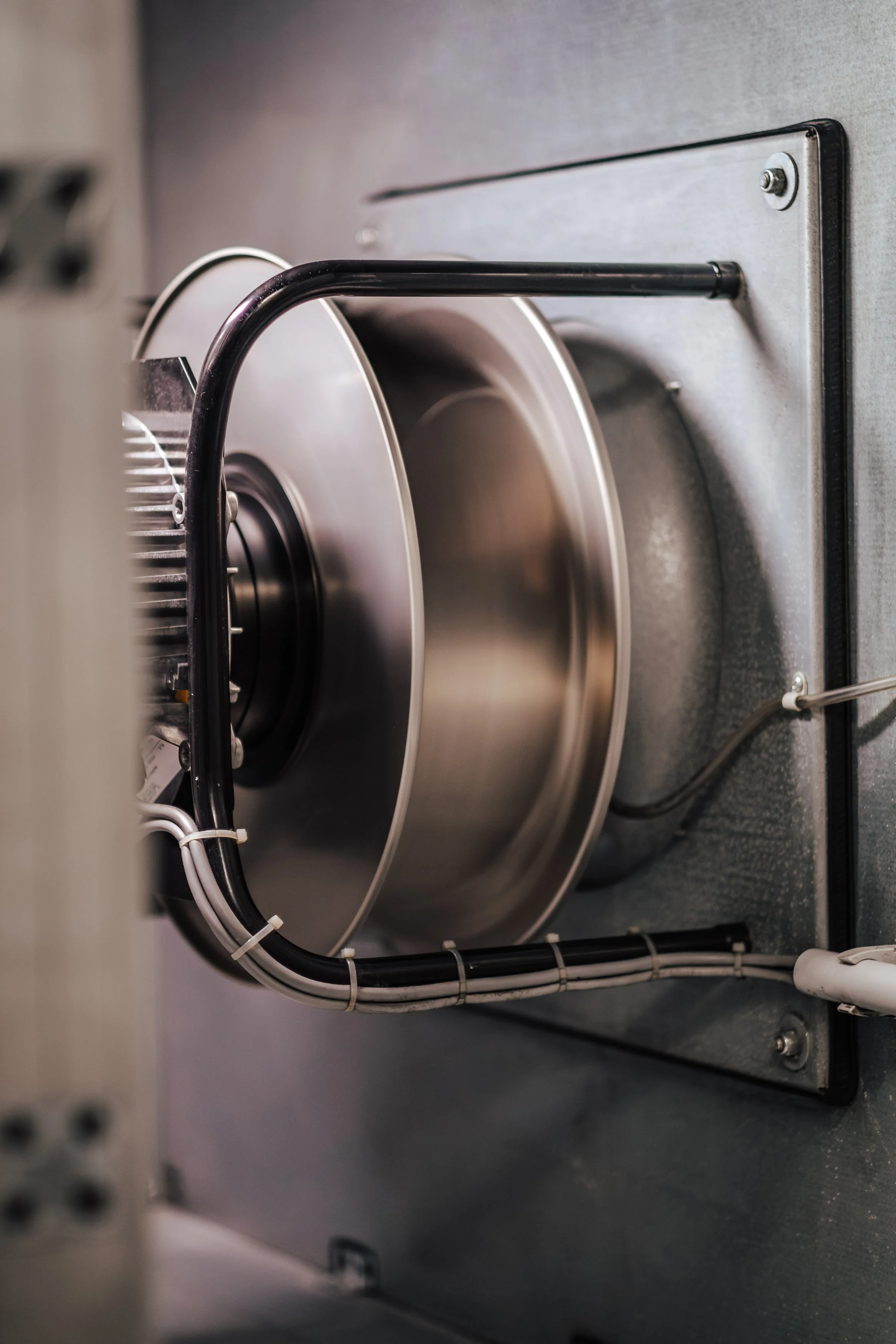 Nahaufnahme eines technischen Geräts mit einem großen, runden Metallteil, mehreren Kabeln und Metallbefestigungen.