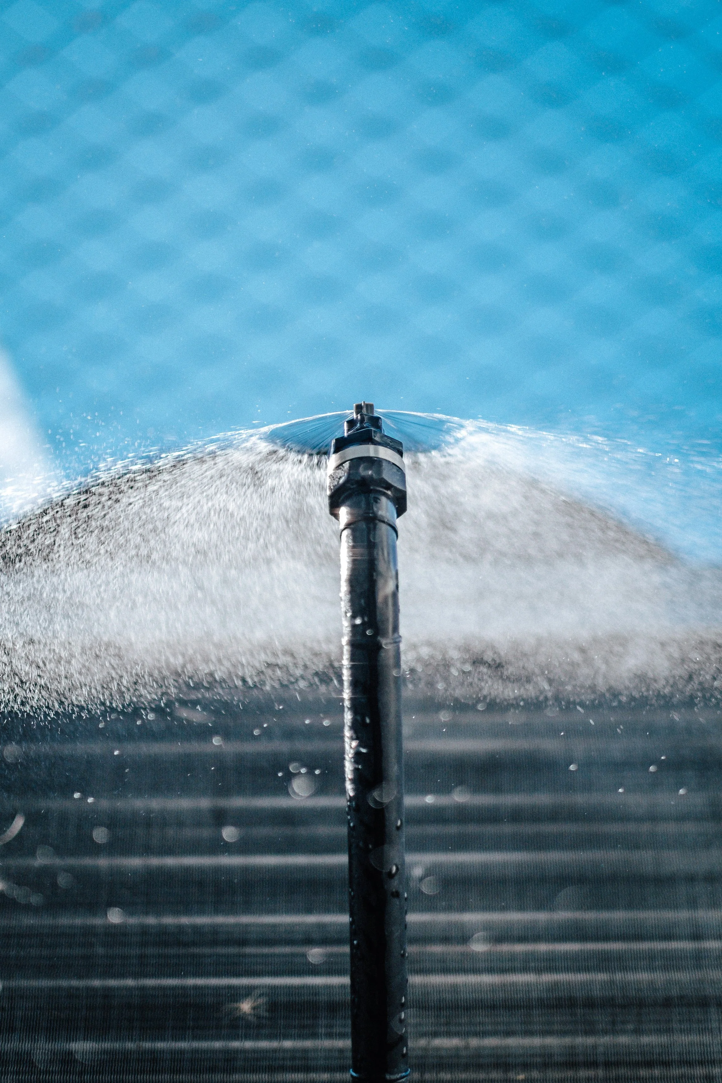 Nahaufnahme eines Wasserstrahls, der aus einer Düse auf Wasseroberfläche sprüht.