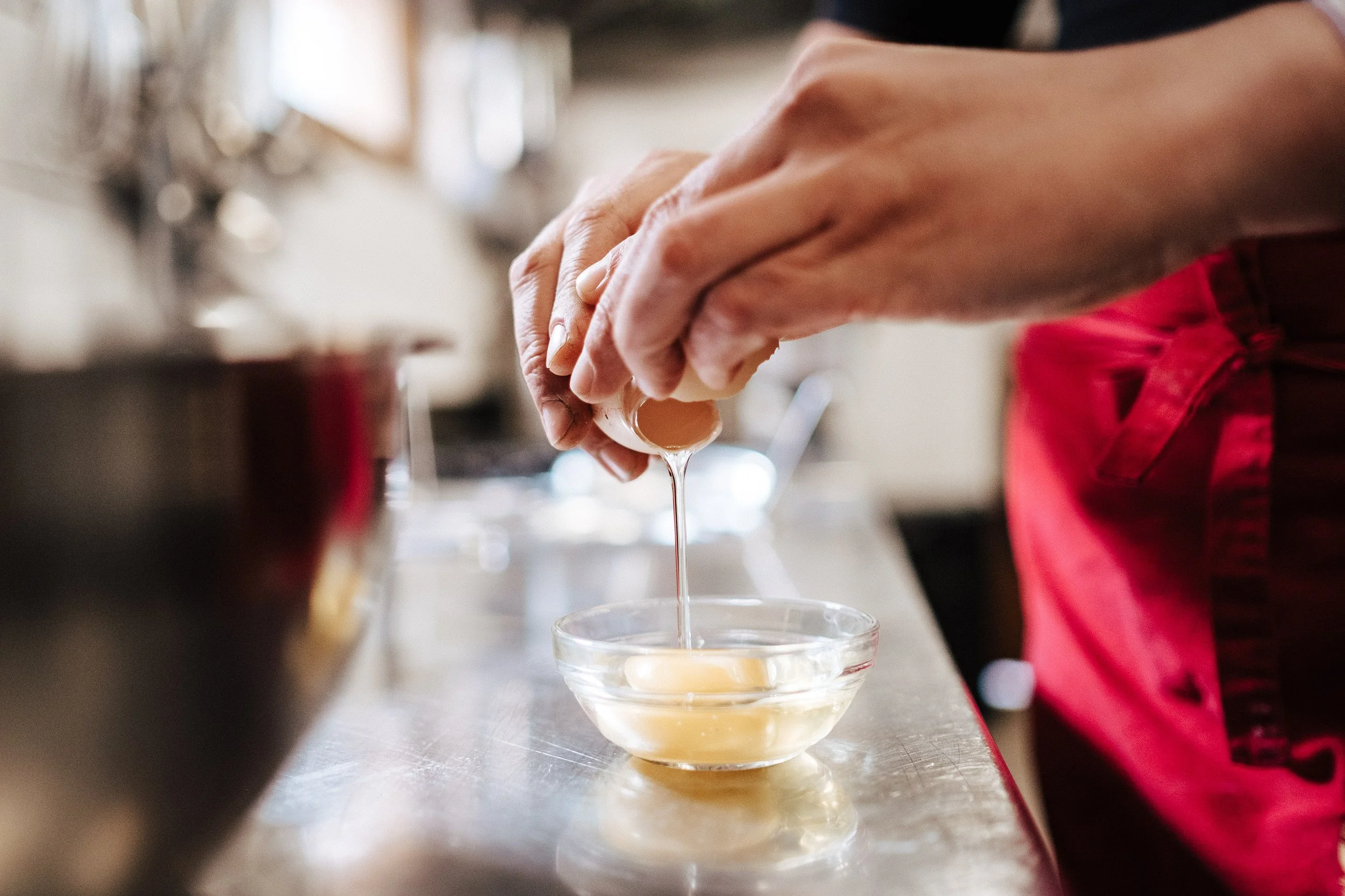Person bricht Eier in eine Schüssel im Küchenumfeld.