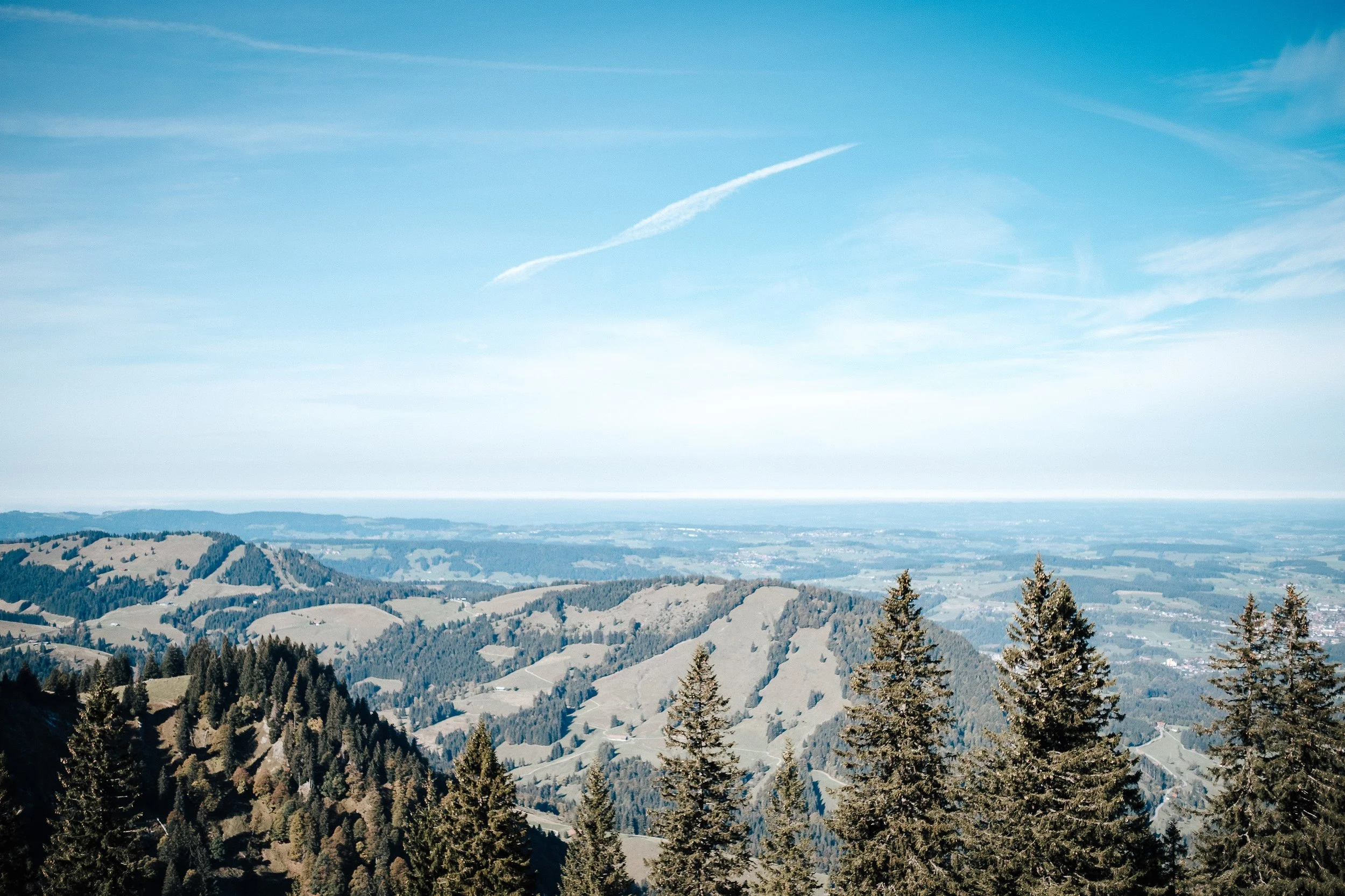 Blick auf Hügel und Wälder unter einem blauen Himmel mit einigen Wölkchen.