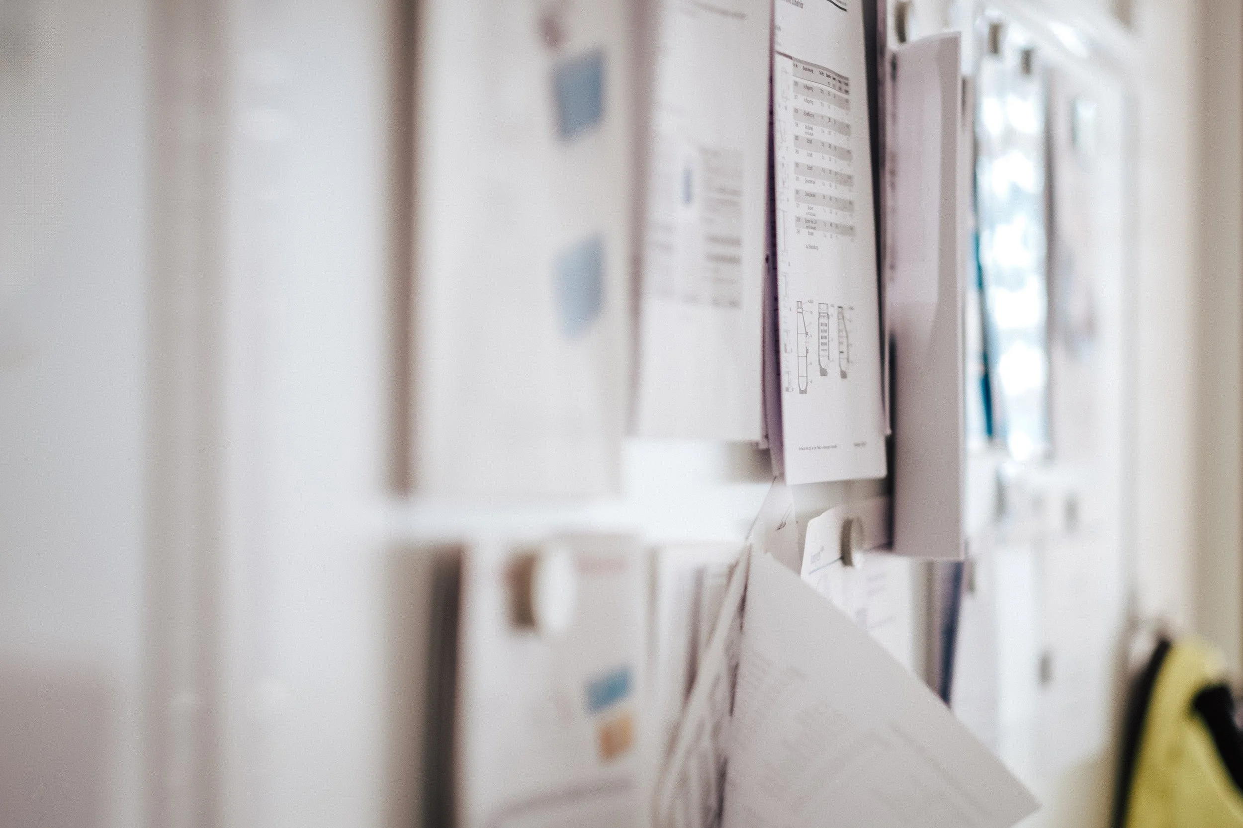 Ein Blick auf eine Pinnwand mit mehreren angebrachten Dokumenten, Notizzetteln und Papierblättern in einem Büro.