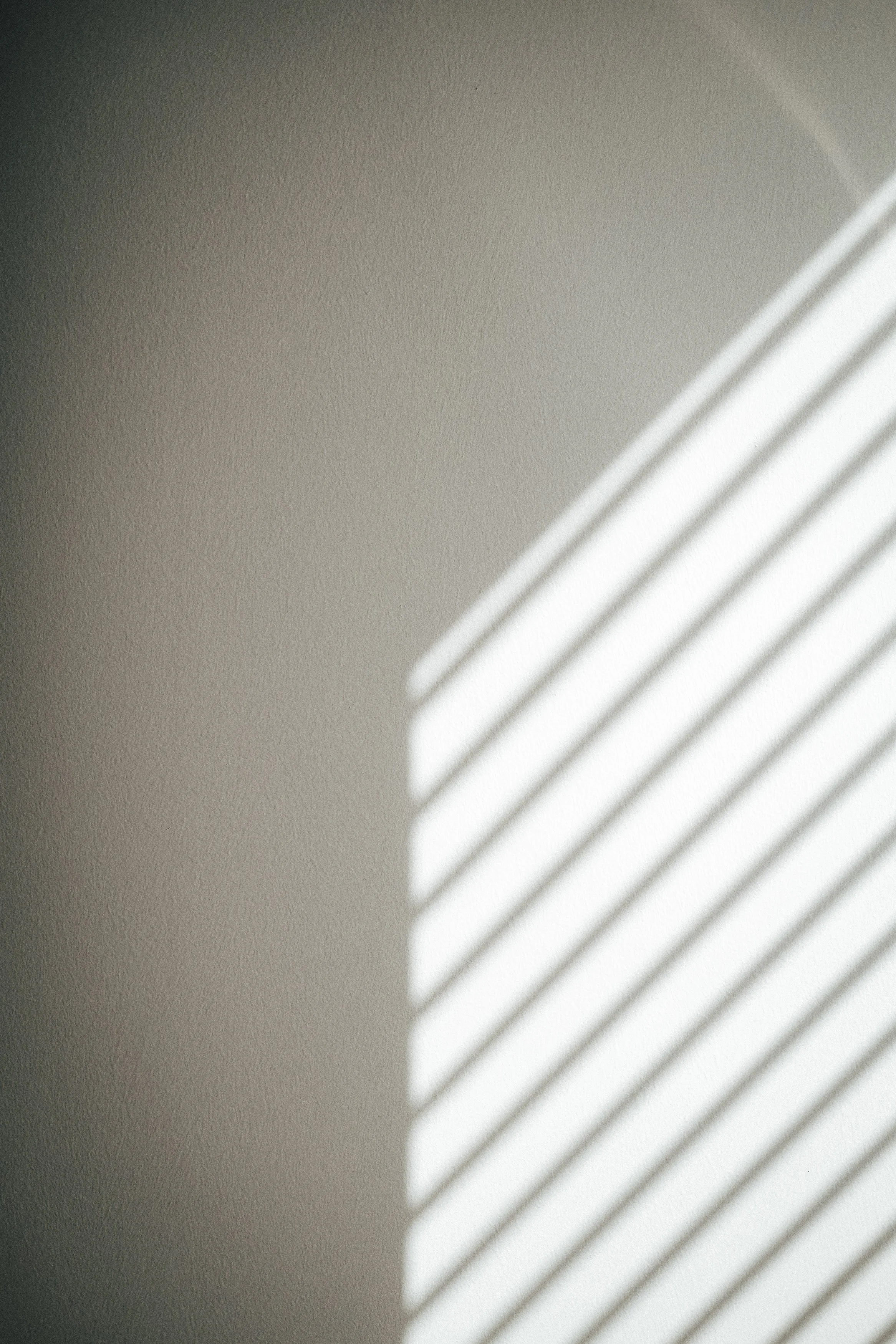 Schatten von Lamellen an einer weißen Wand